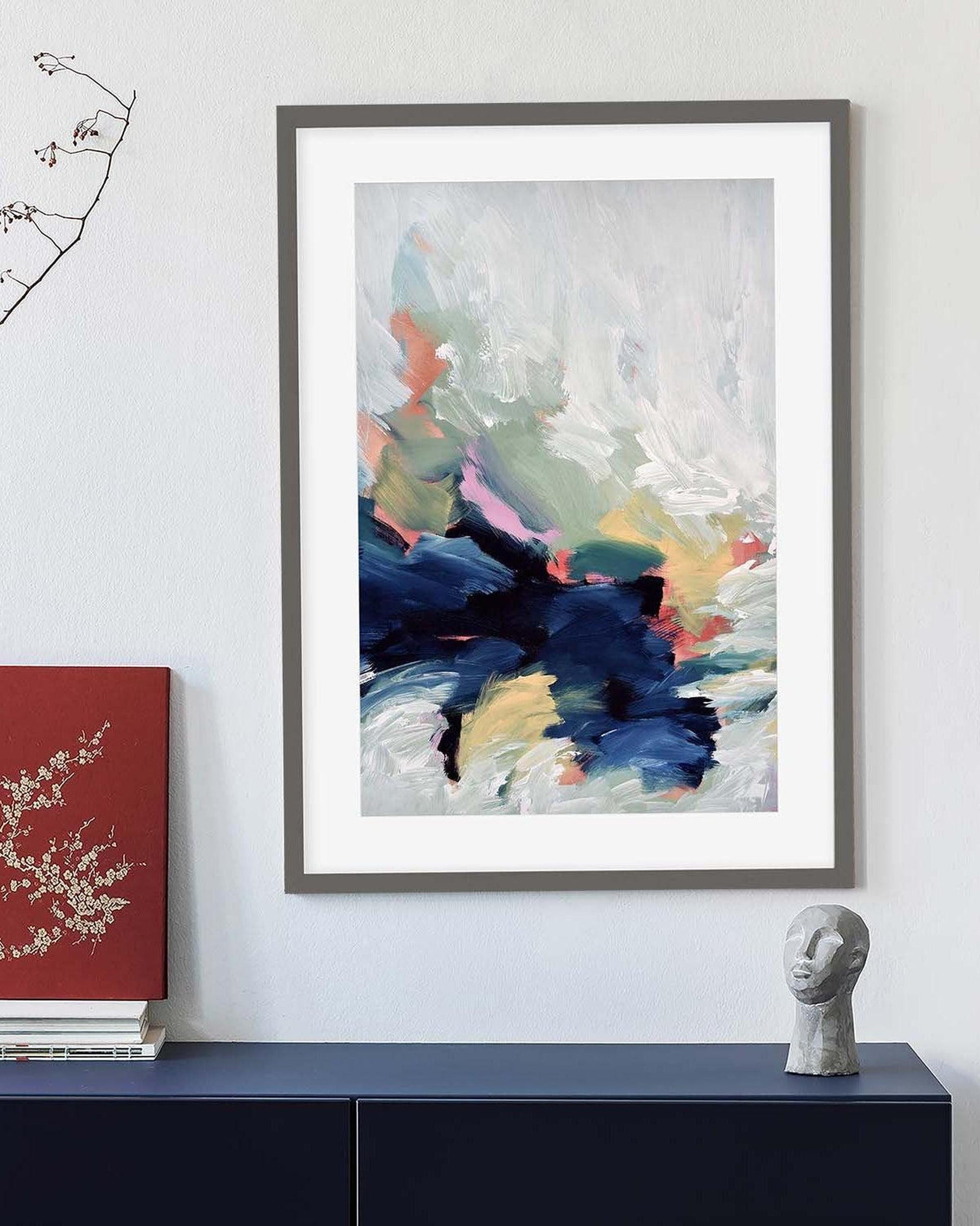 Framed abstract art on a wall above a console table with decorative items.