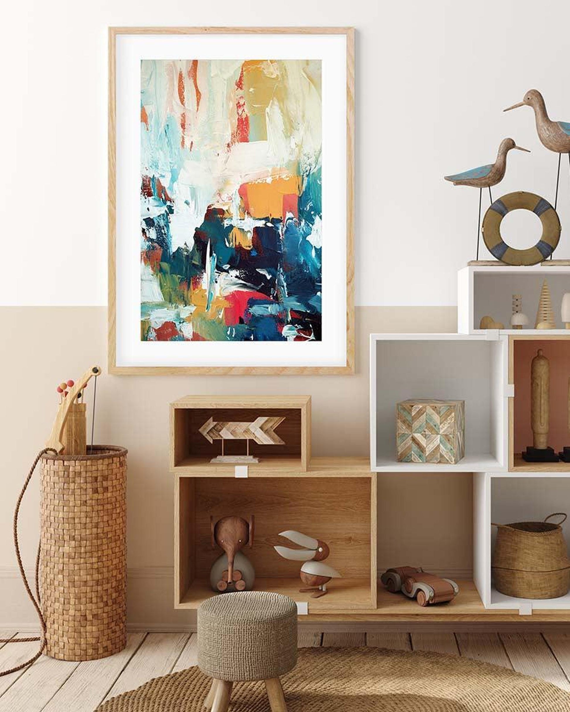 Colorful abstract painting in a wooden frame on a wall above a shelf with decorative items.