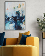Yellow armchair with blue pillows in a room with abstract art on the wall.
