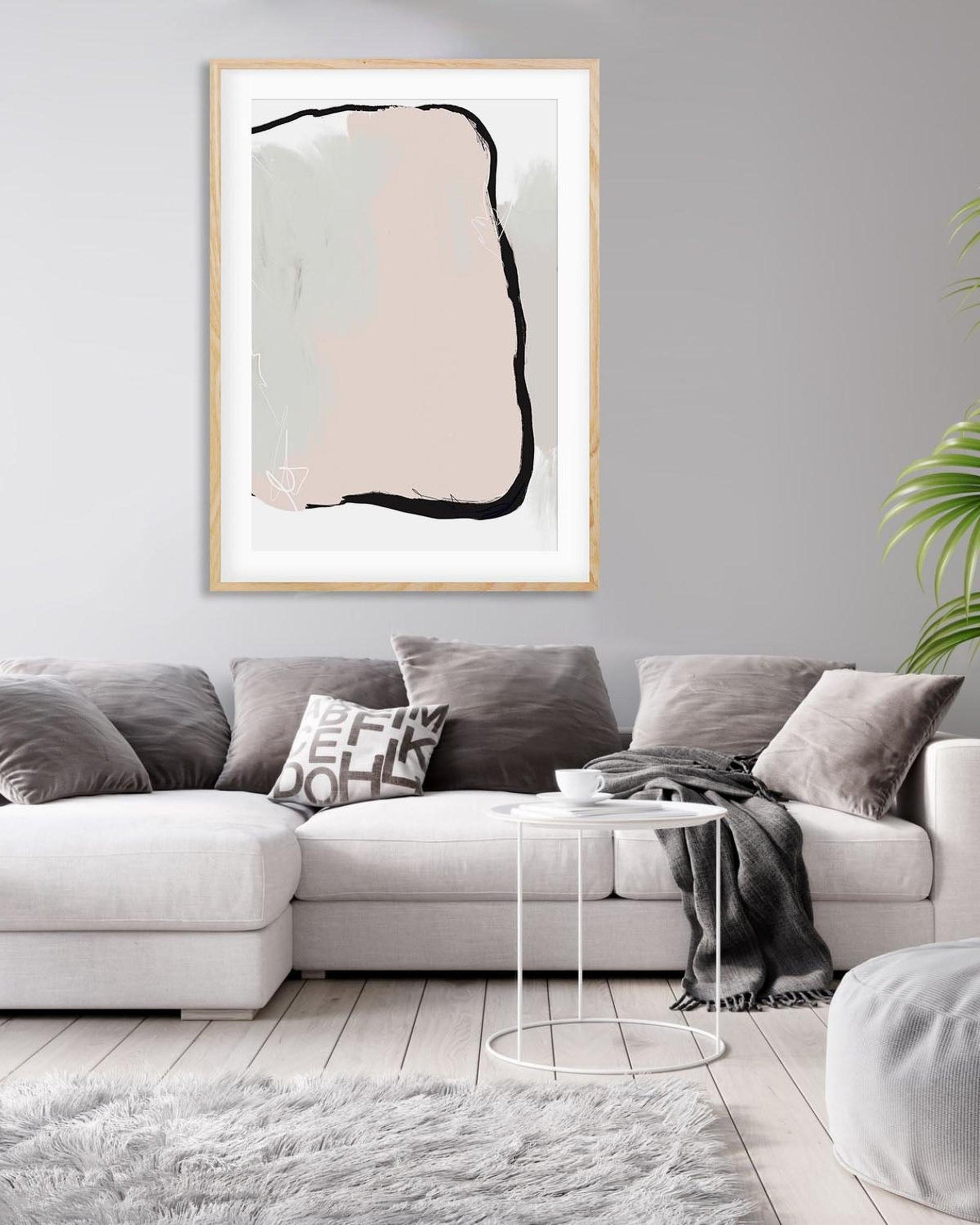 Living room with a gray sectional sofa, abstract art on the wall, and a small round table.