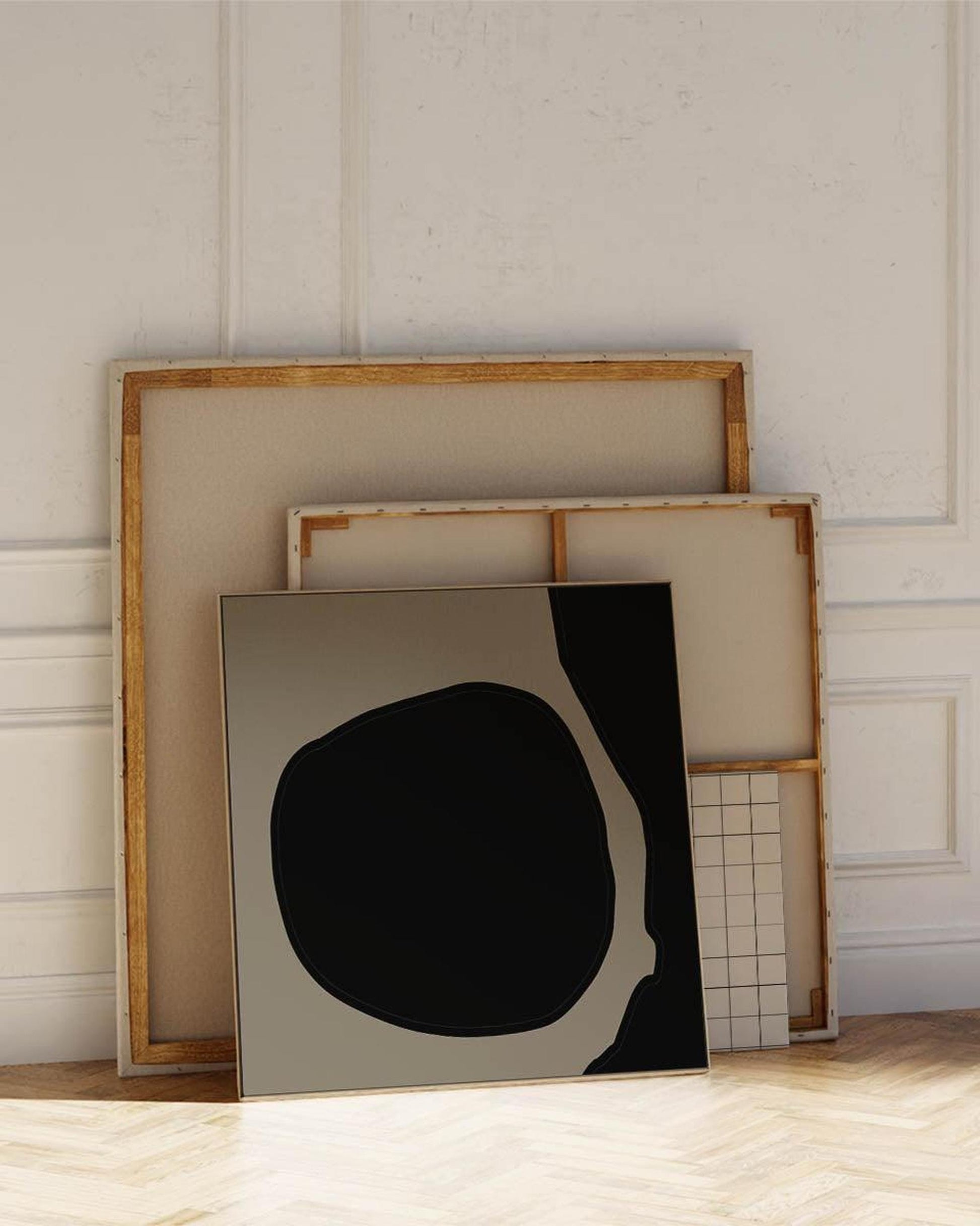 Set of framed artworks on a wooden floor with a neutral wall background