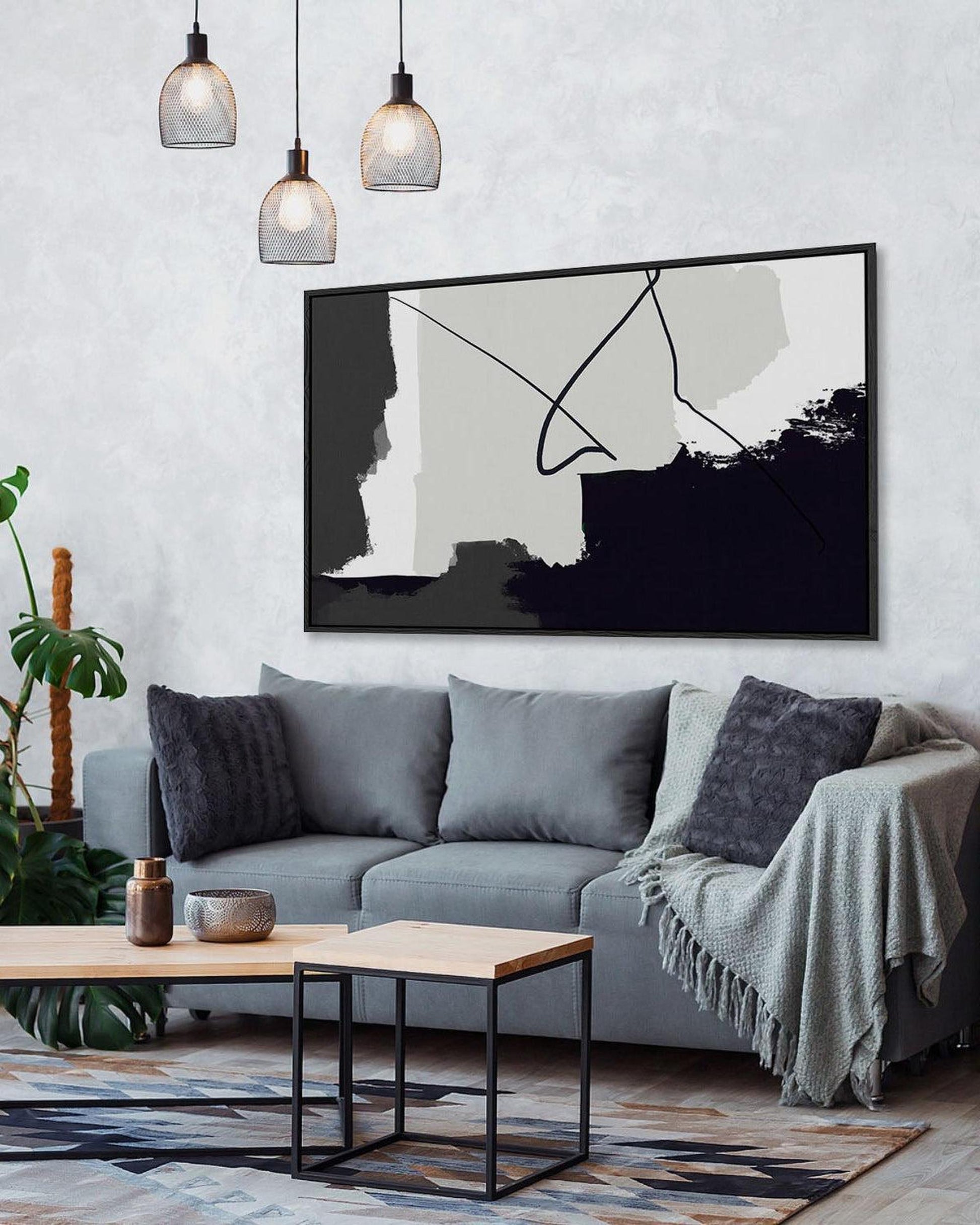 Modern living room with gray sofa, abstract art, and decorative plants.