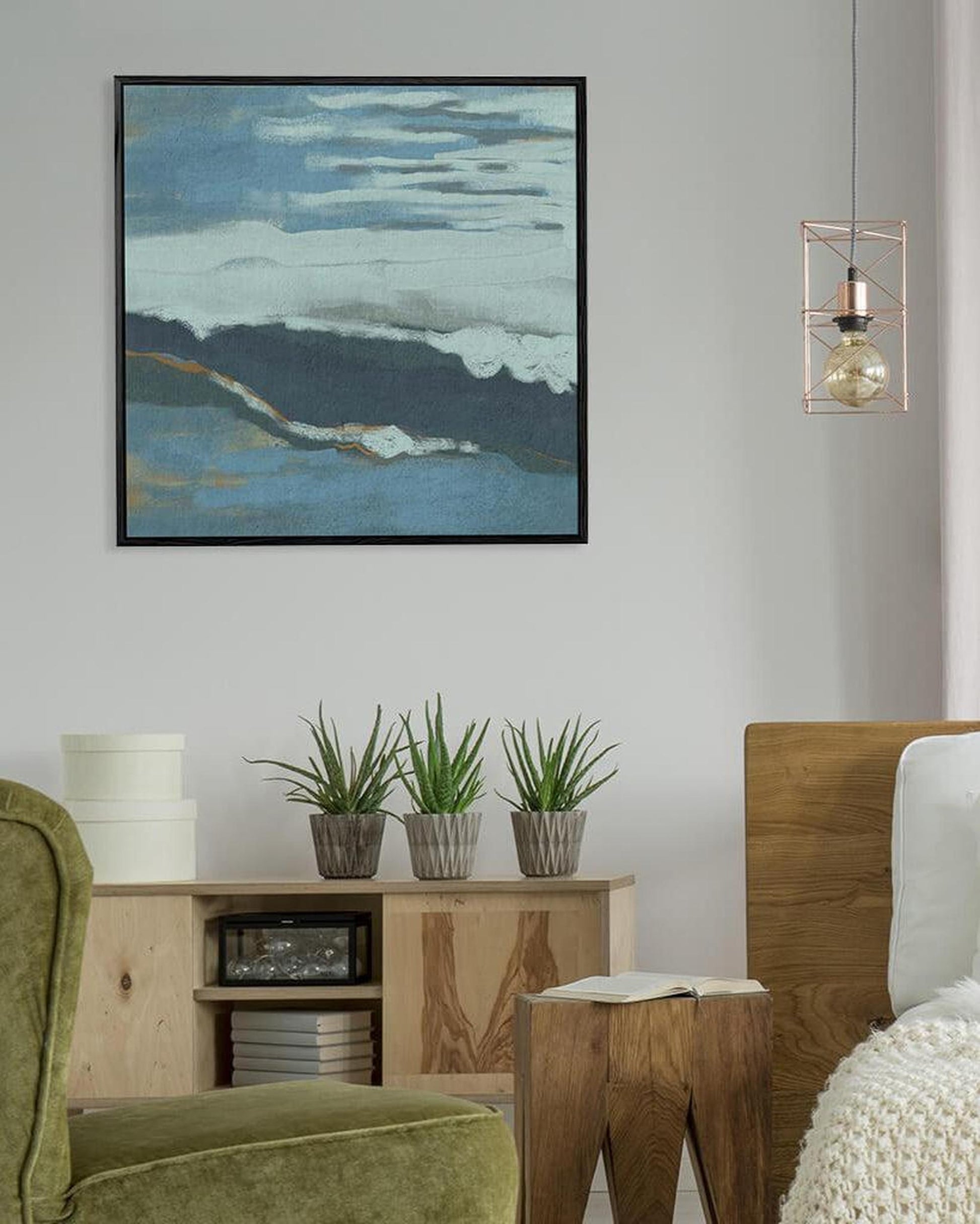 Living room with a painting of a landscape on the wall, plants on a wooden cabinet, and a green armchair.