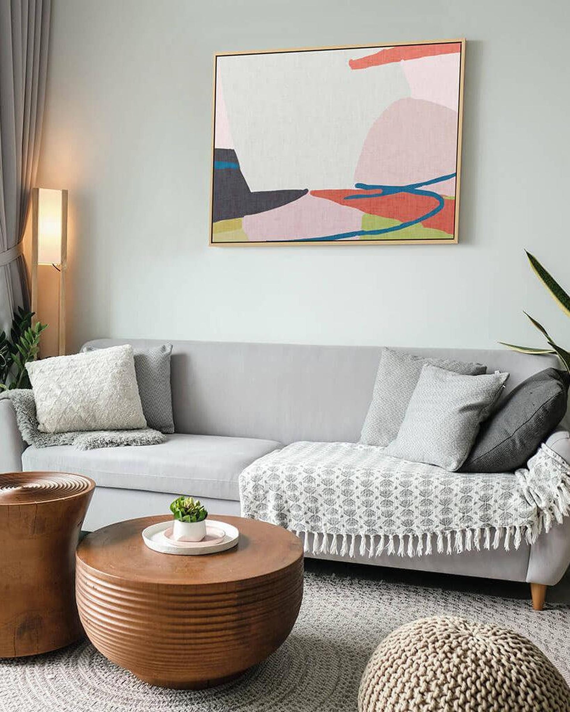 Living room with a gray sofa, wooden coffee table, and abstract art on the wall.