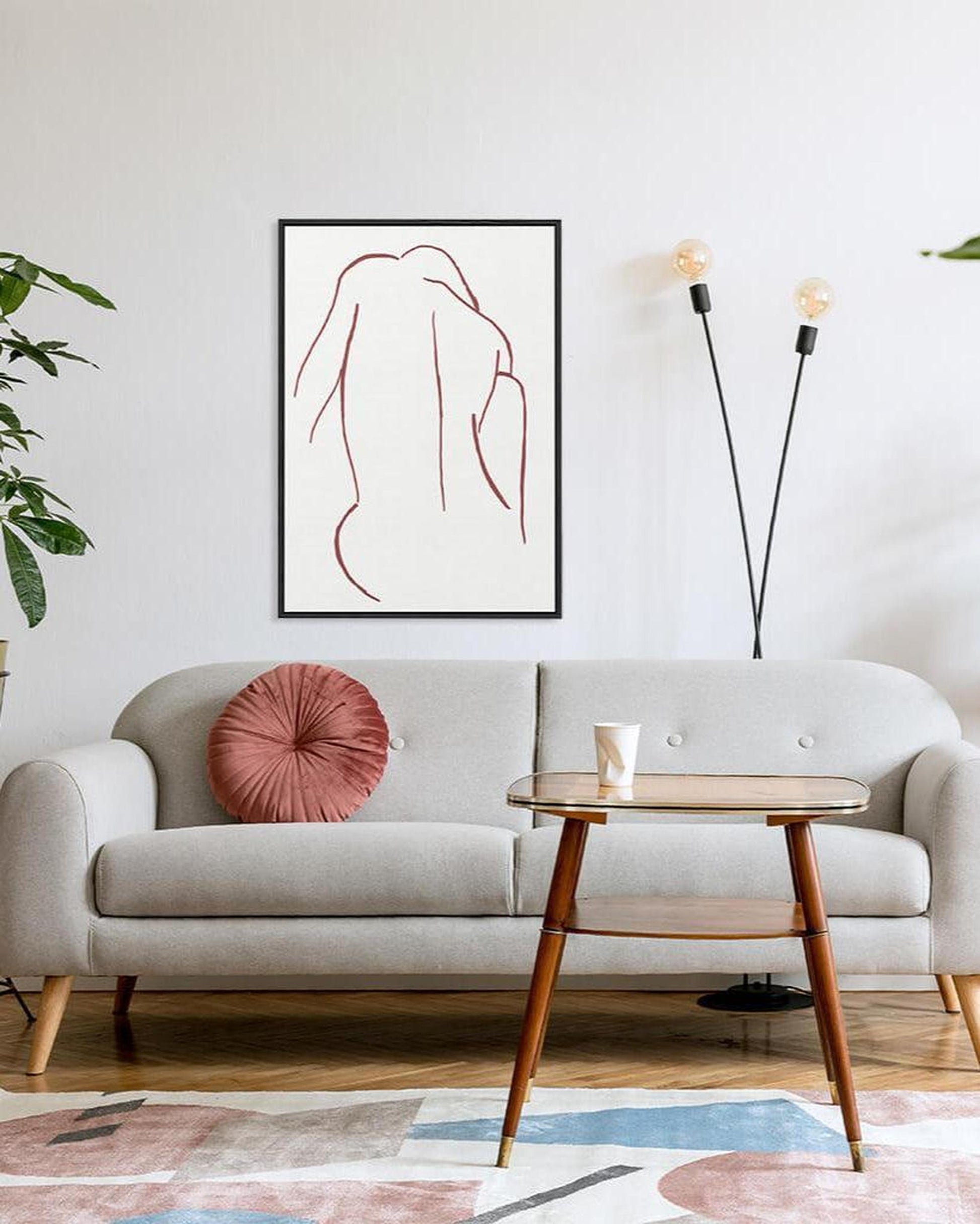 Modern living room with a gray sofa, pink pillow, and abstract art on the wall.