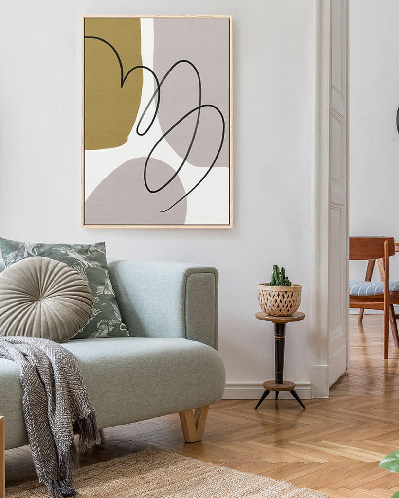 Modern living room with a gray sofa, abstract art, and a small table with a plant.