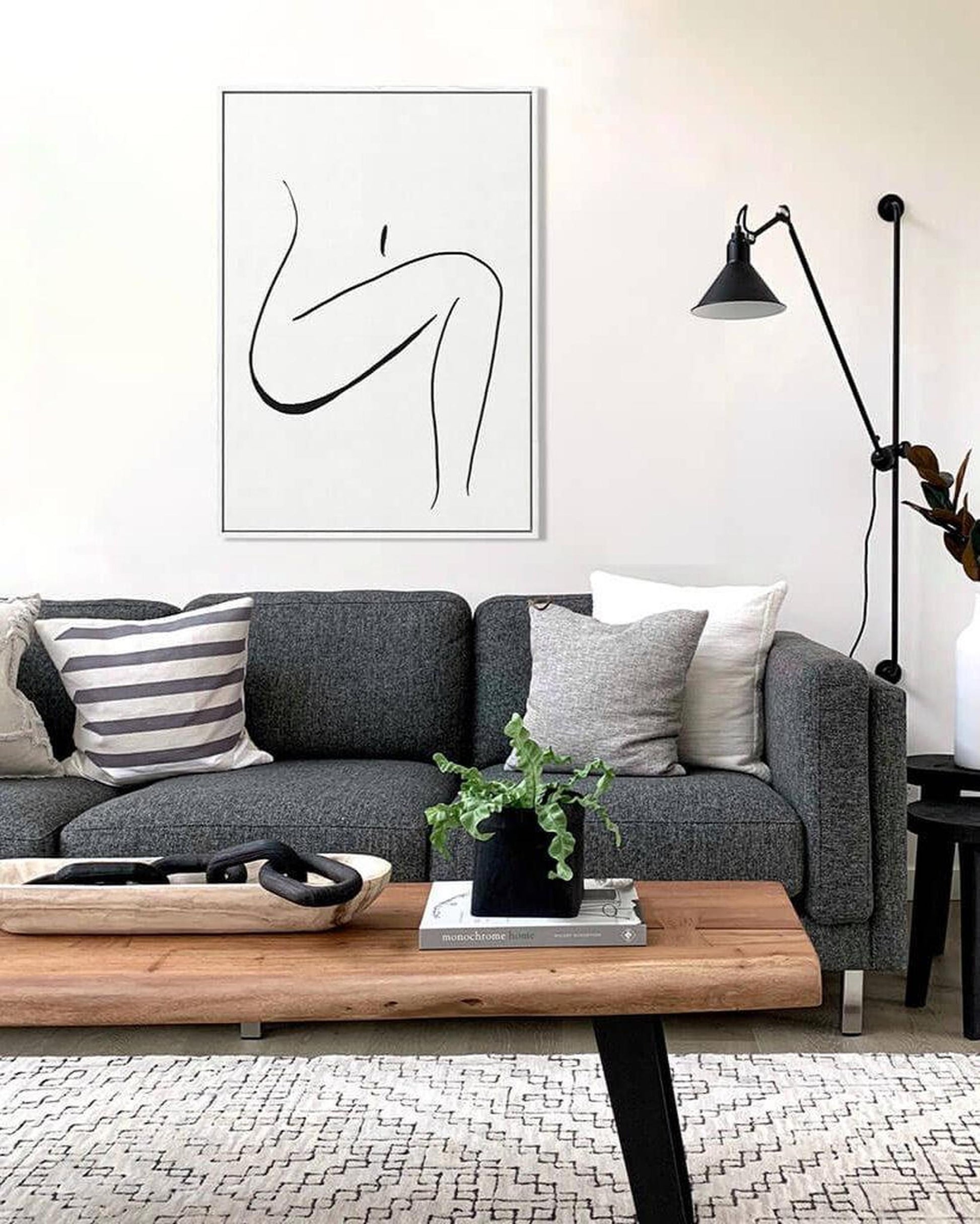 Modern living room with gray sofa, wooden coffee table, and abstract art on wall.