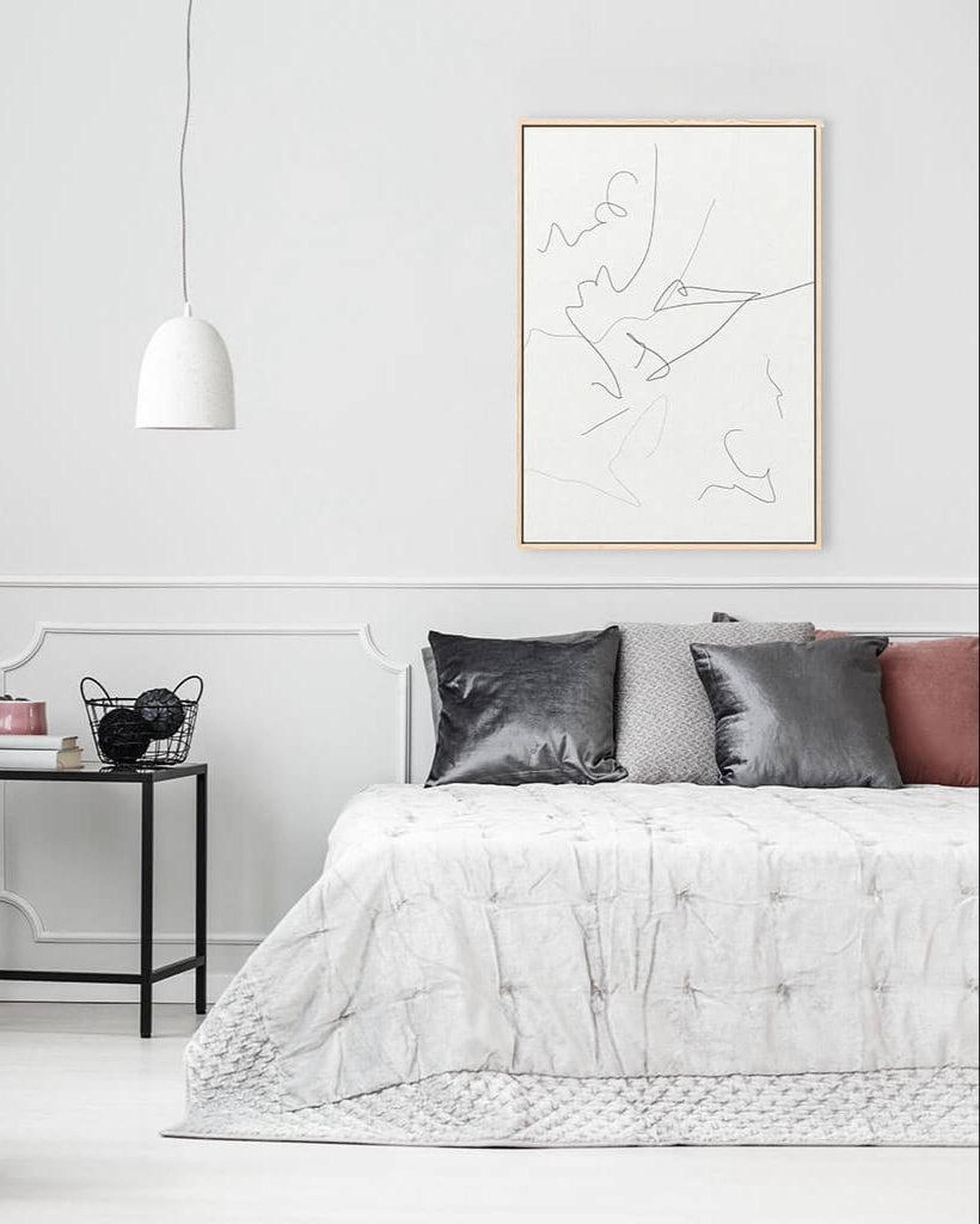 Modern bedroom with a bed, abstract art on the wall, and a side table.