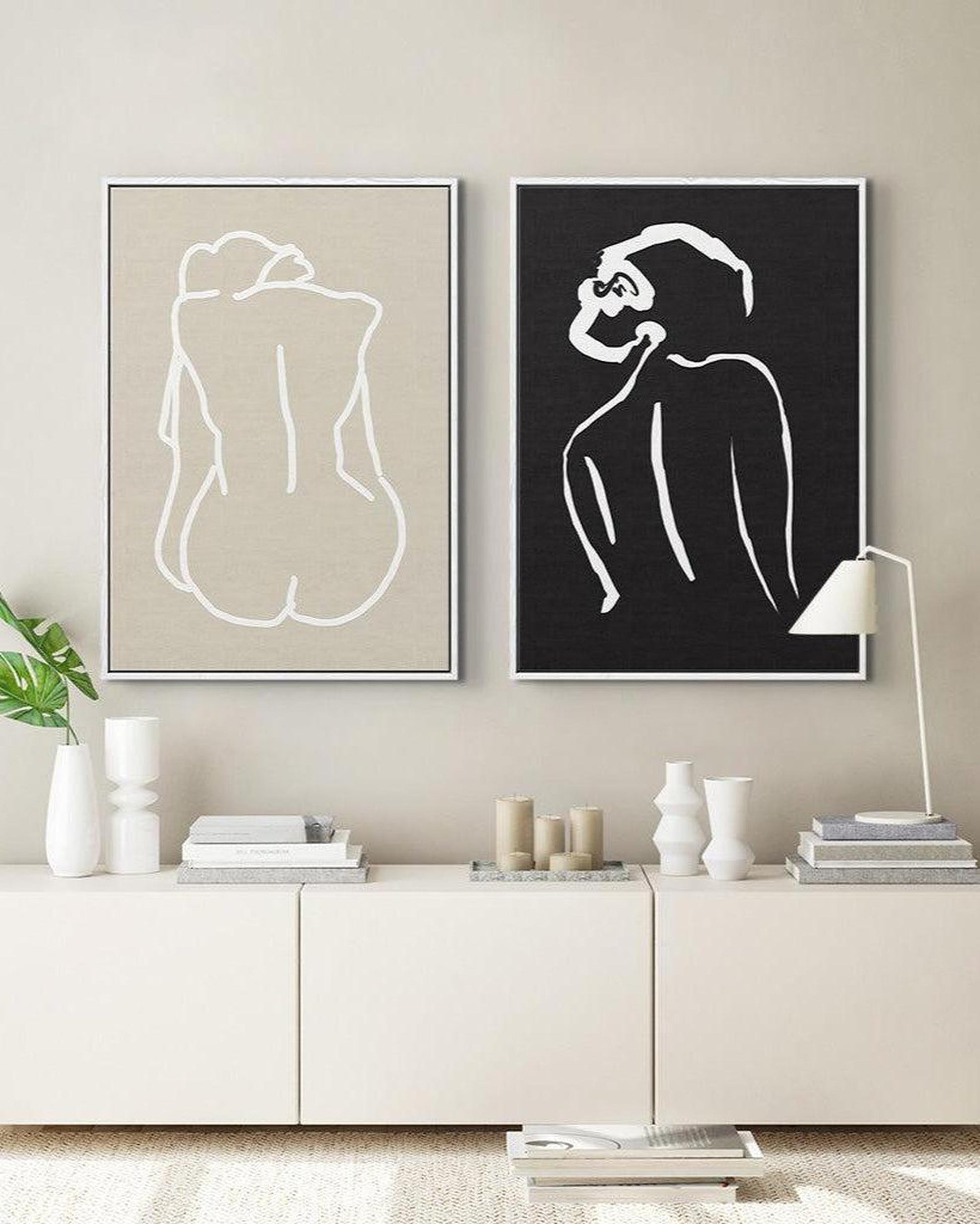 Two abstract line art prints on a wall above a white cabinet.