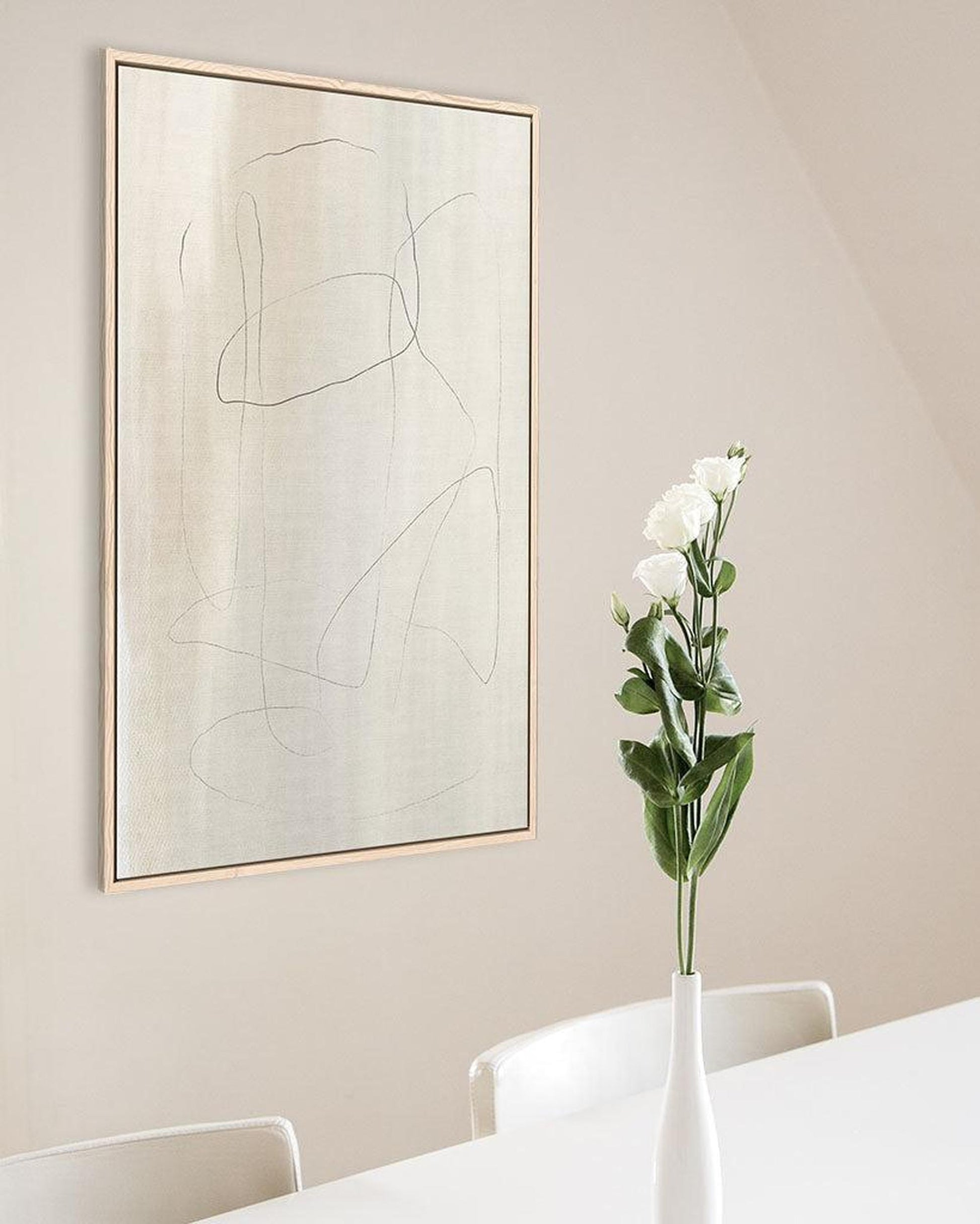 Abstract artwork on a wall with a vase of flowers in the foreground