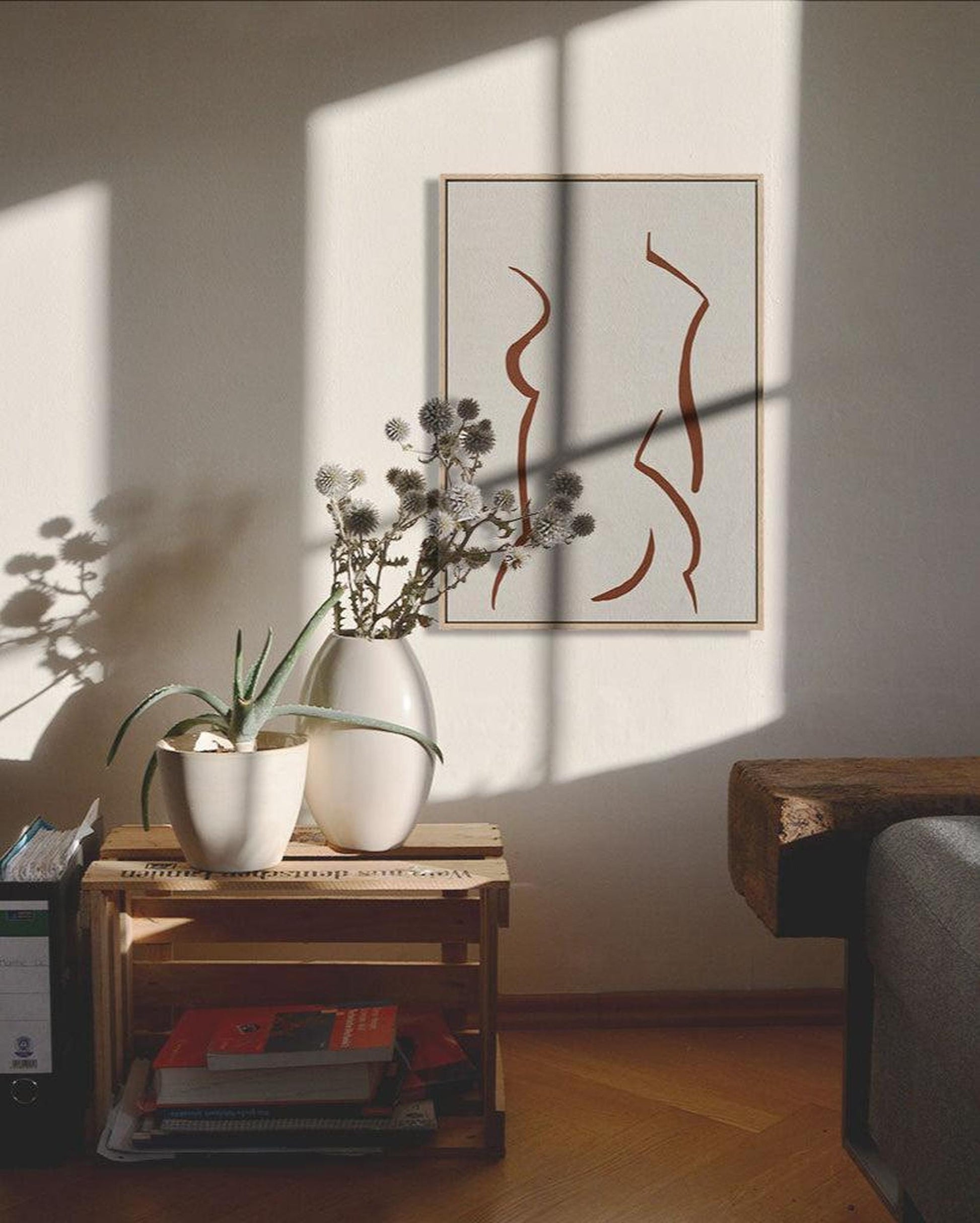 Vase with flowers on a wooden crate against a wall with abstract art