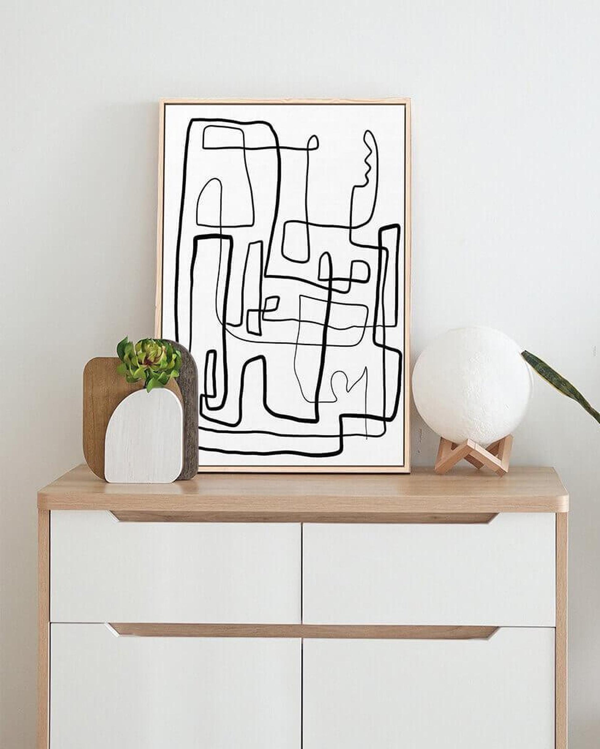 Abstract line art print on a wooden shelf with decorative items