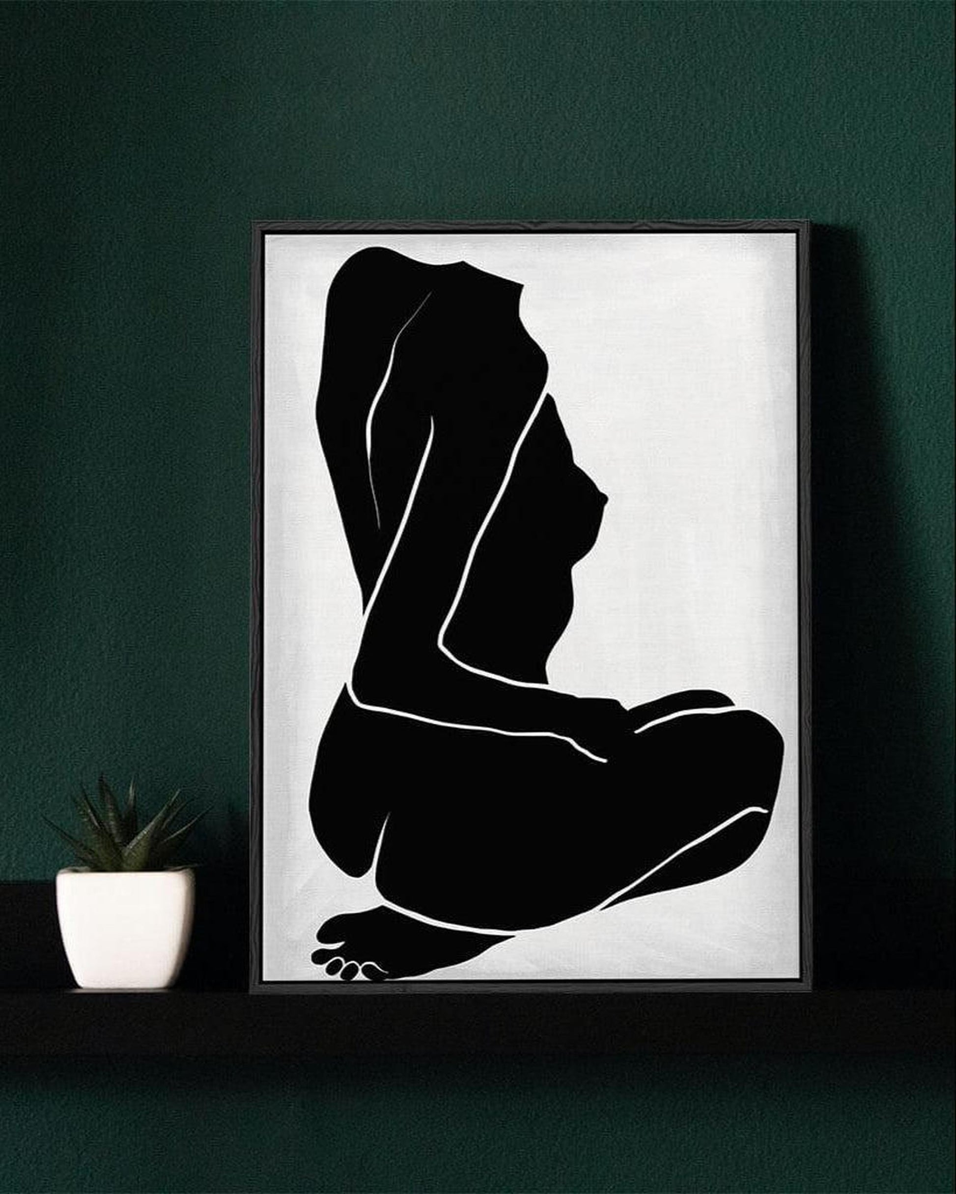 Framed black and white silhouette art of a person on a dark green wall.