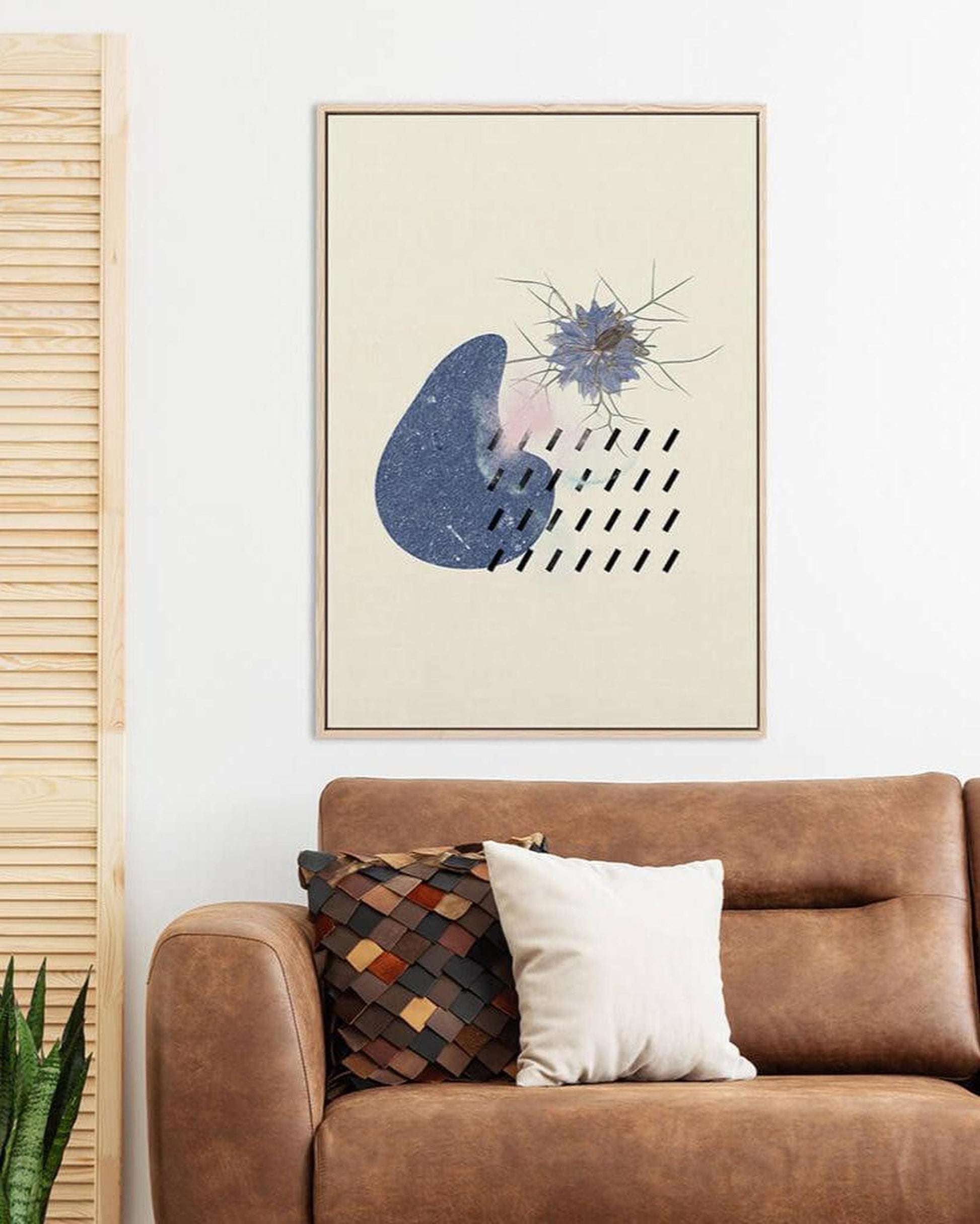 Framed abstract art above a brown sofa with decorative pillows