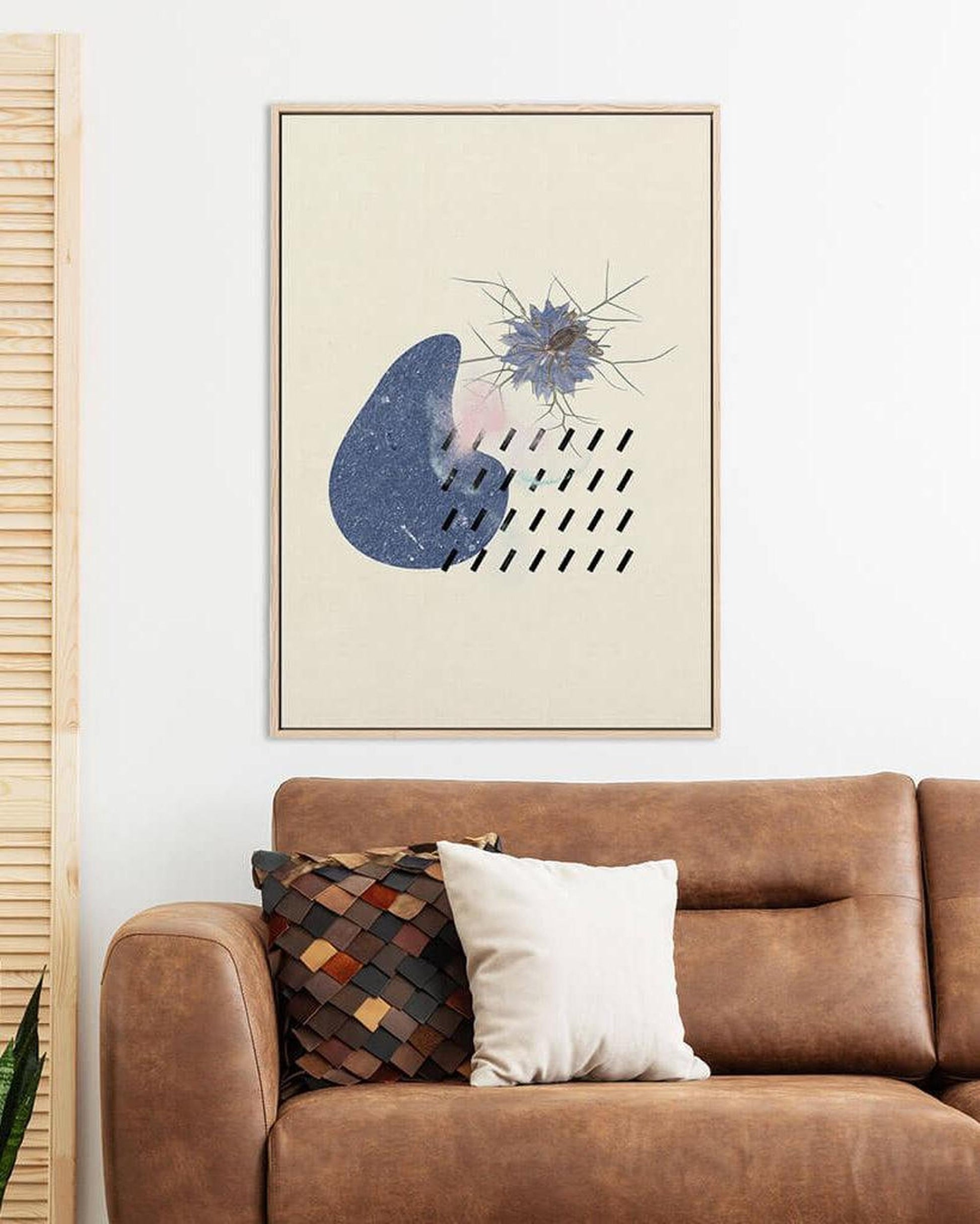 Framed abstract art above a brown sofa with decorative pillows