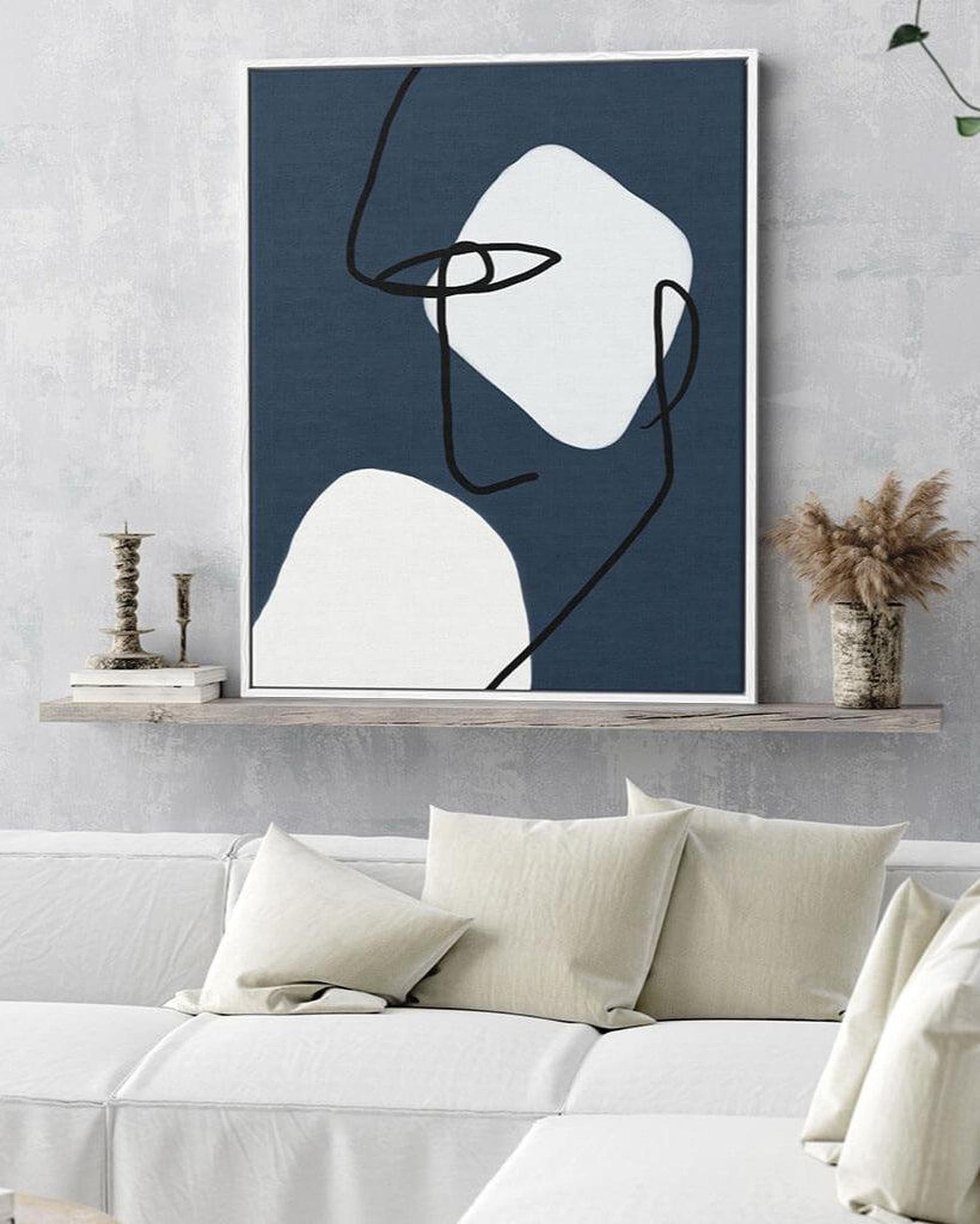 Abstract art print on a wall above a bed with neutral decor