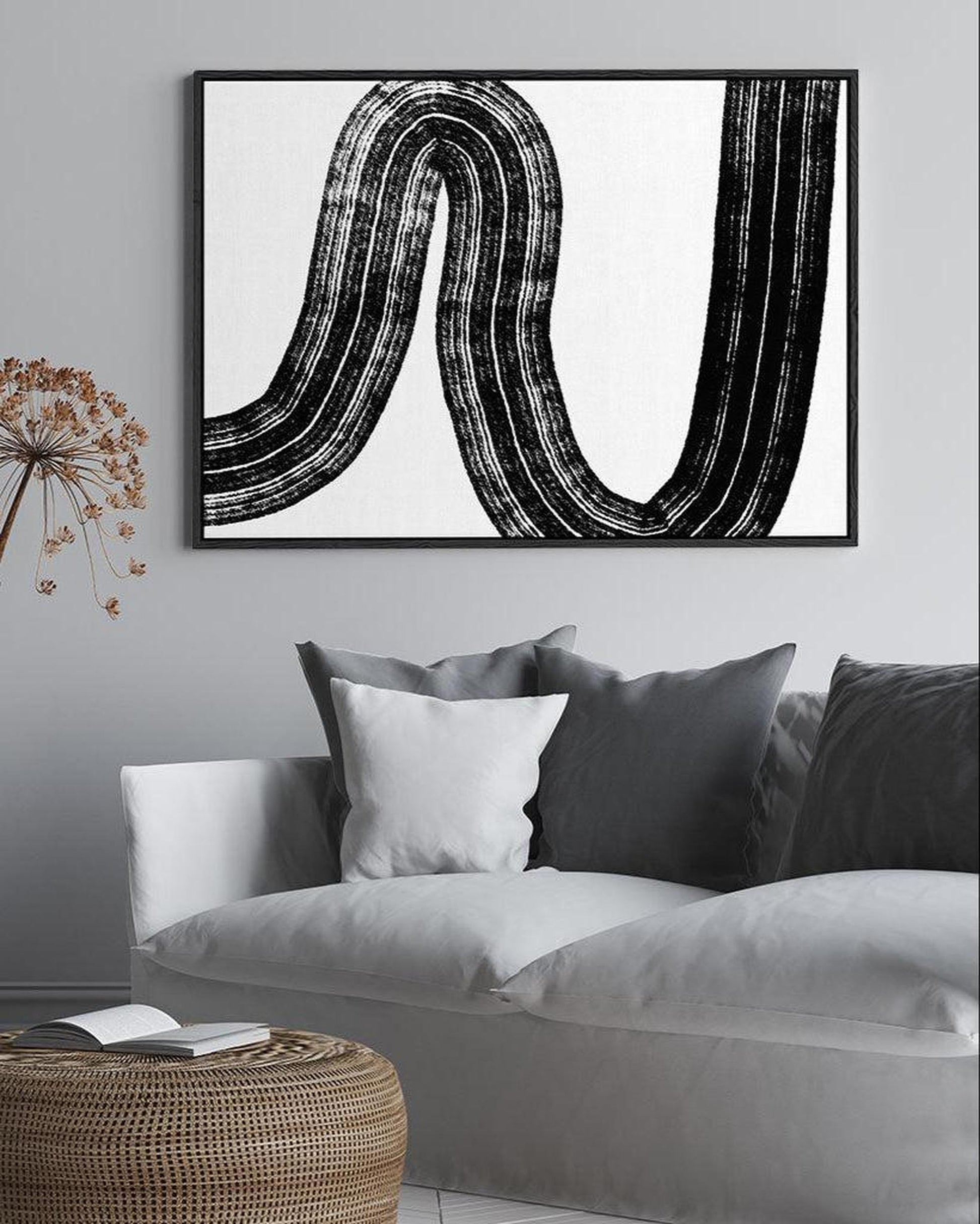 Abstract black and white artwork on a wall above a sofa in a living room.