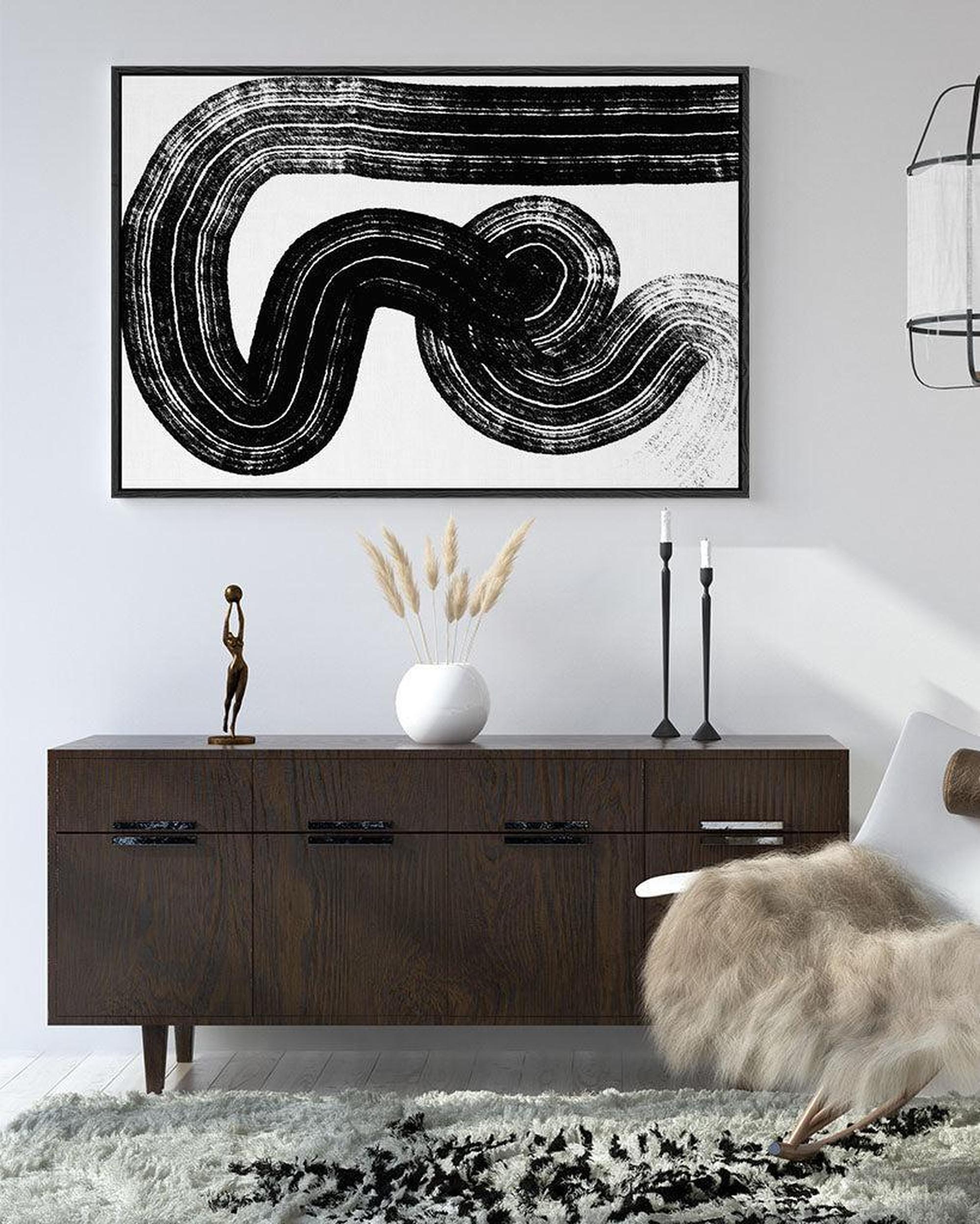 Modern interior with abstract black and white artwork on the wall above a wooden console table.