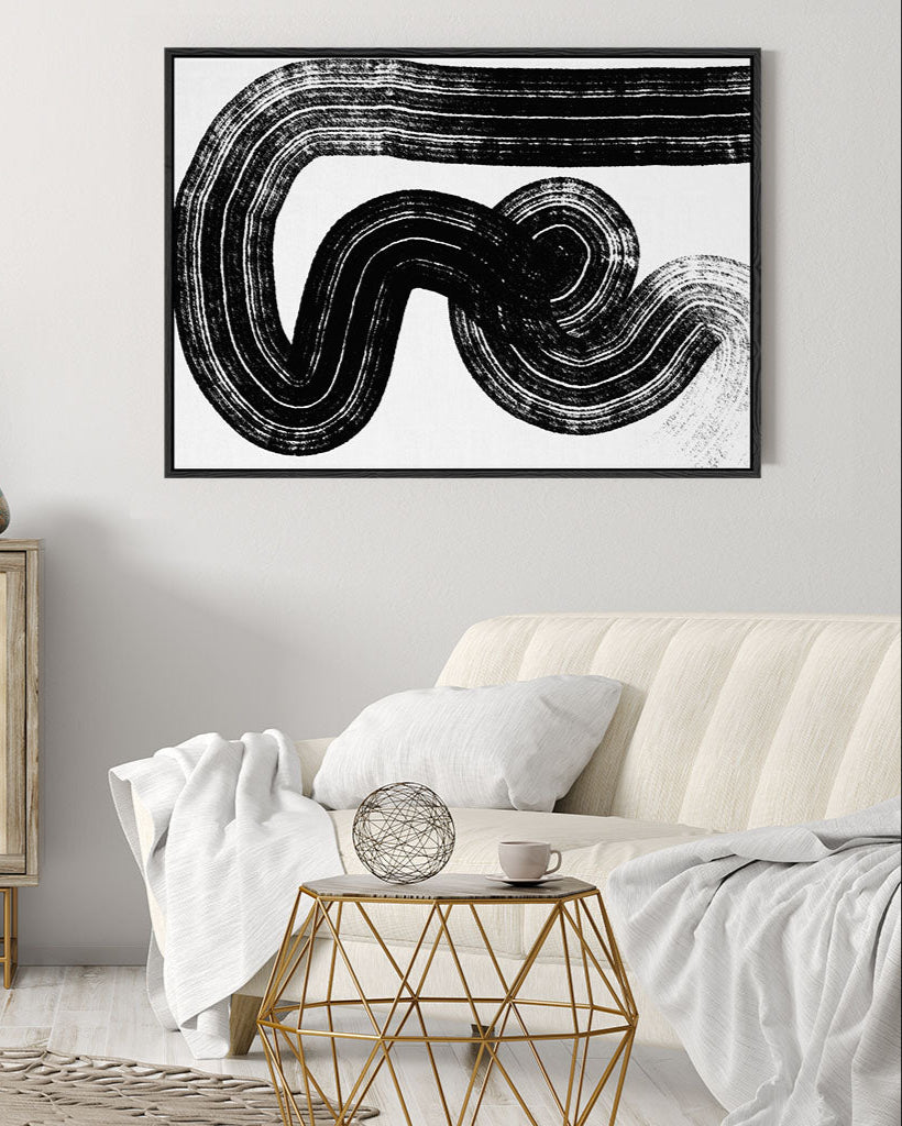 Abstract black and white artwork on a wall above a sofa in a living room.