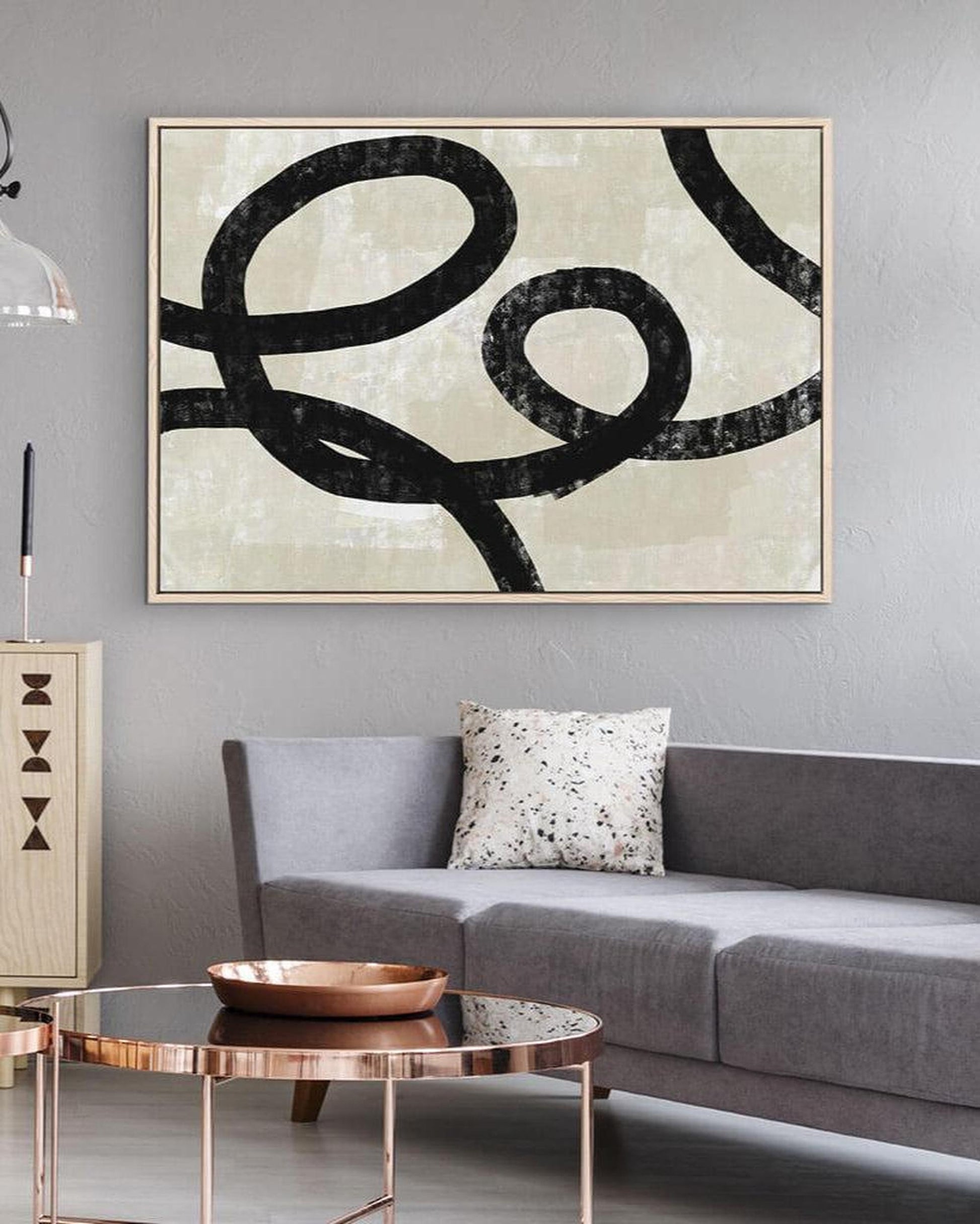 Abstract art piece on a gray wall above a sofa in a living room.