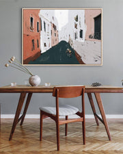 Wooden dining table with chair against a gray wall with a framed painting of a city street.