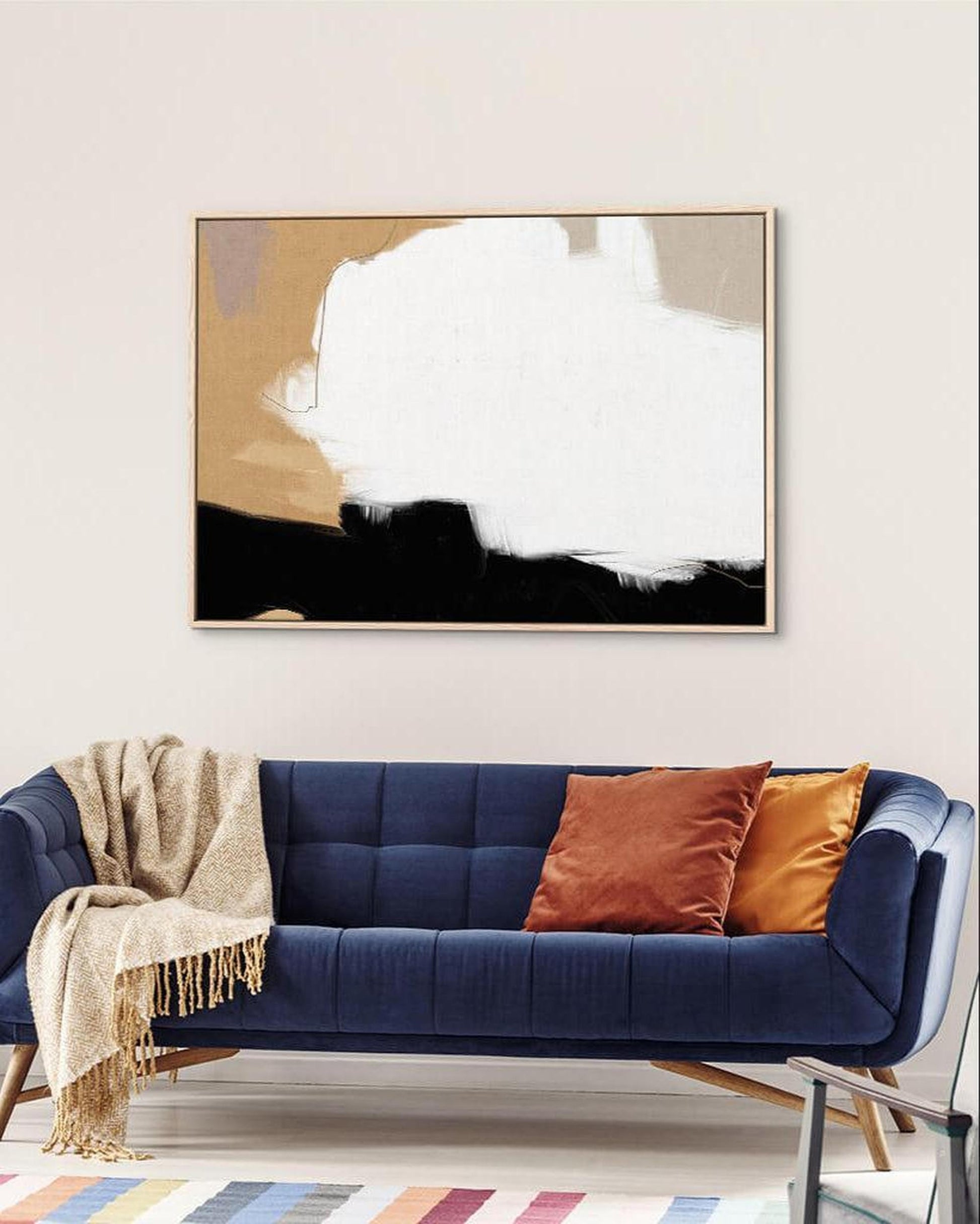 Navy blue sofa with colorful cushions and a abstract painting on the wall in a living room.