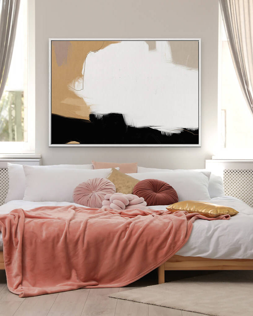 Modern bedroom with abstract art on the wall, pink blanket, and colorful pillows.