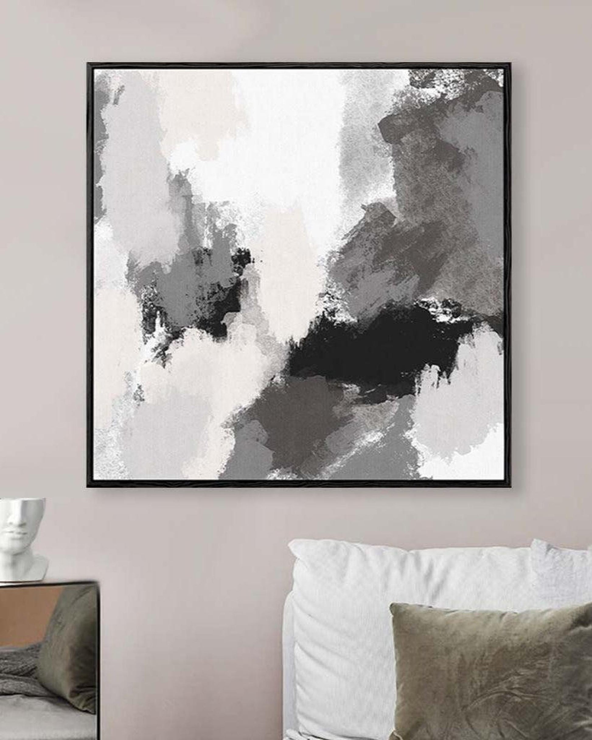 Abstract art print in a black frame on a wall above a sofa.