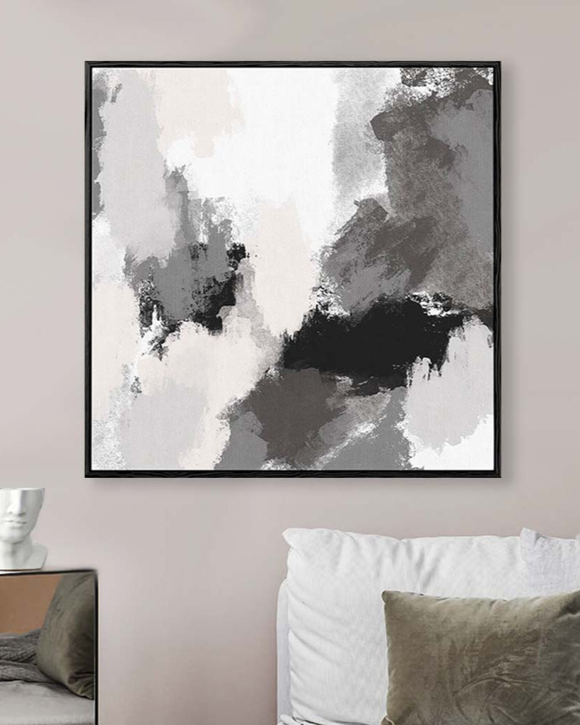 Abstract art print in a black frame on a wall above a sofa.