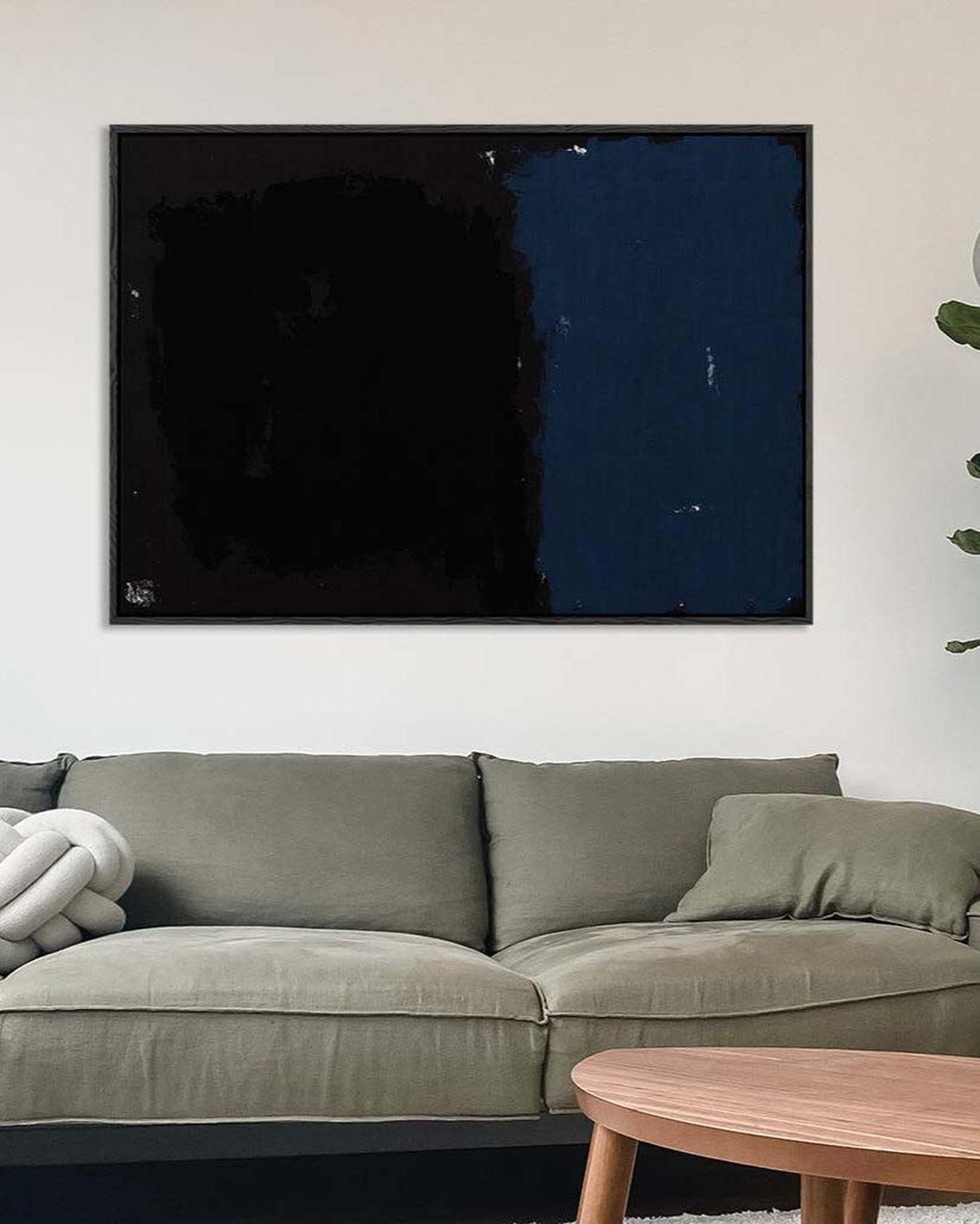Abstract art piece on a wall above a gray sofa in a living room.