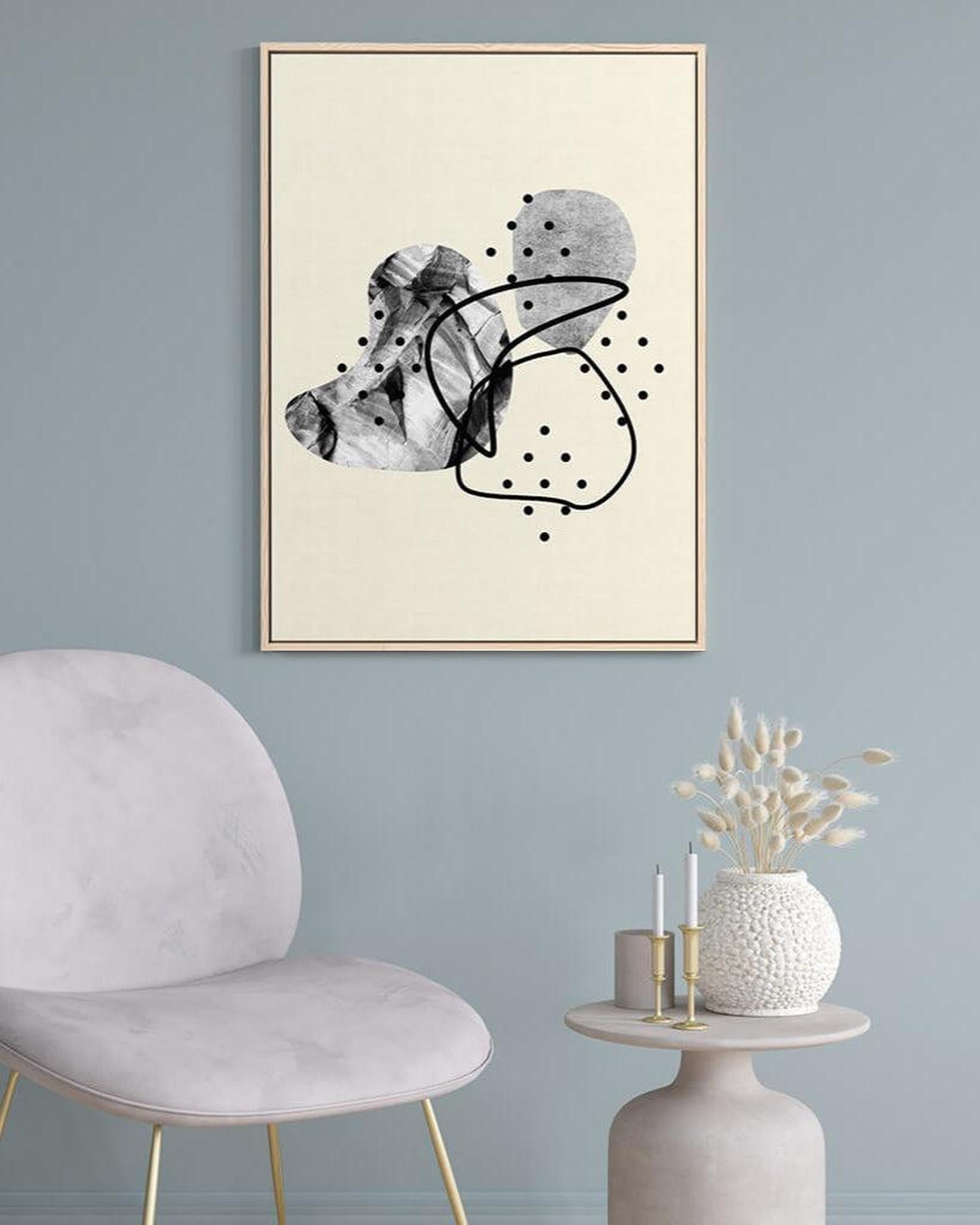 Abstract art print on a wall with a chair and table in the foreground