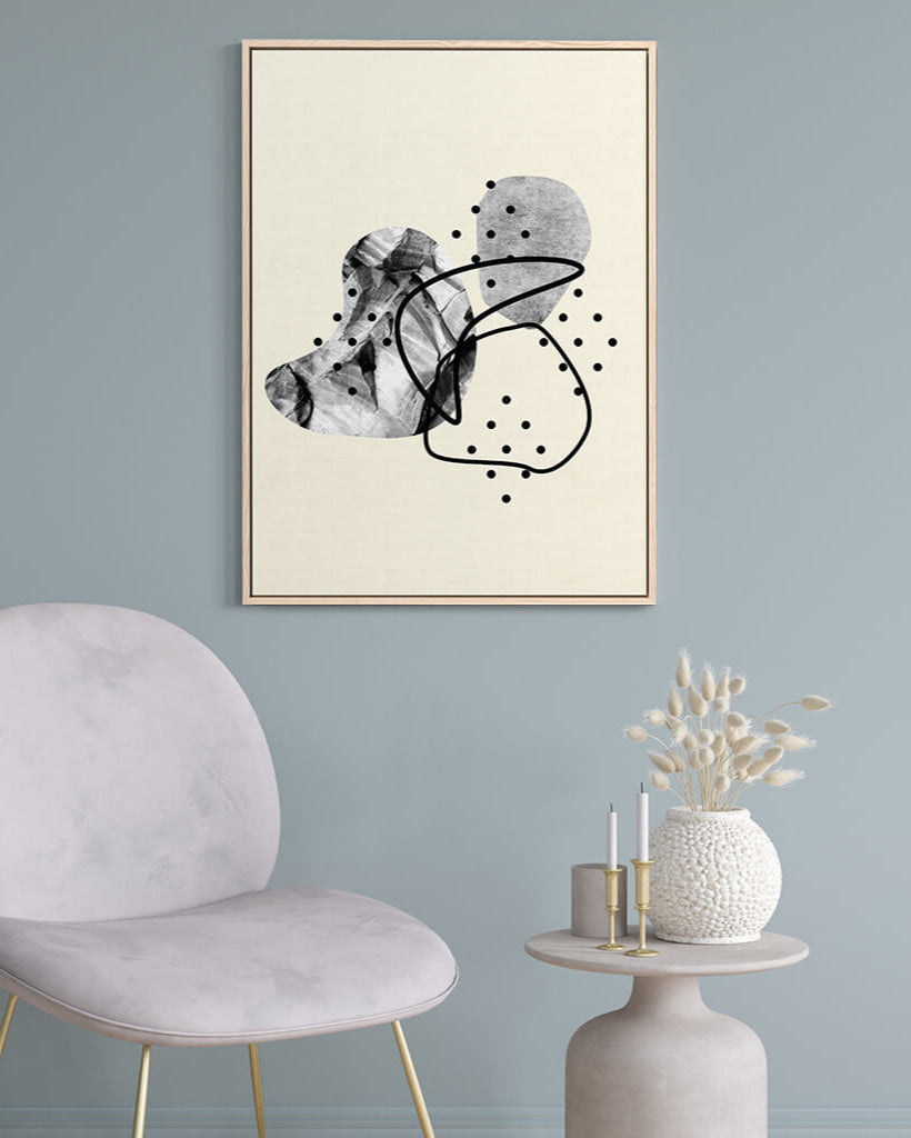 Abstract art print on a wall with a chair and table in the foreground
