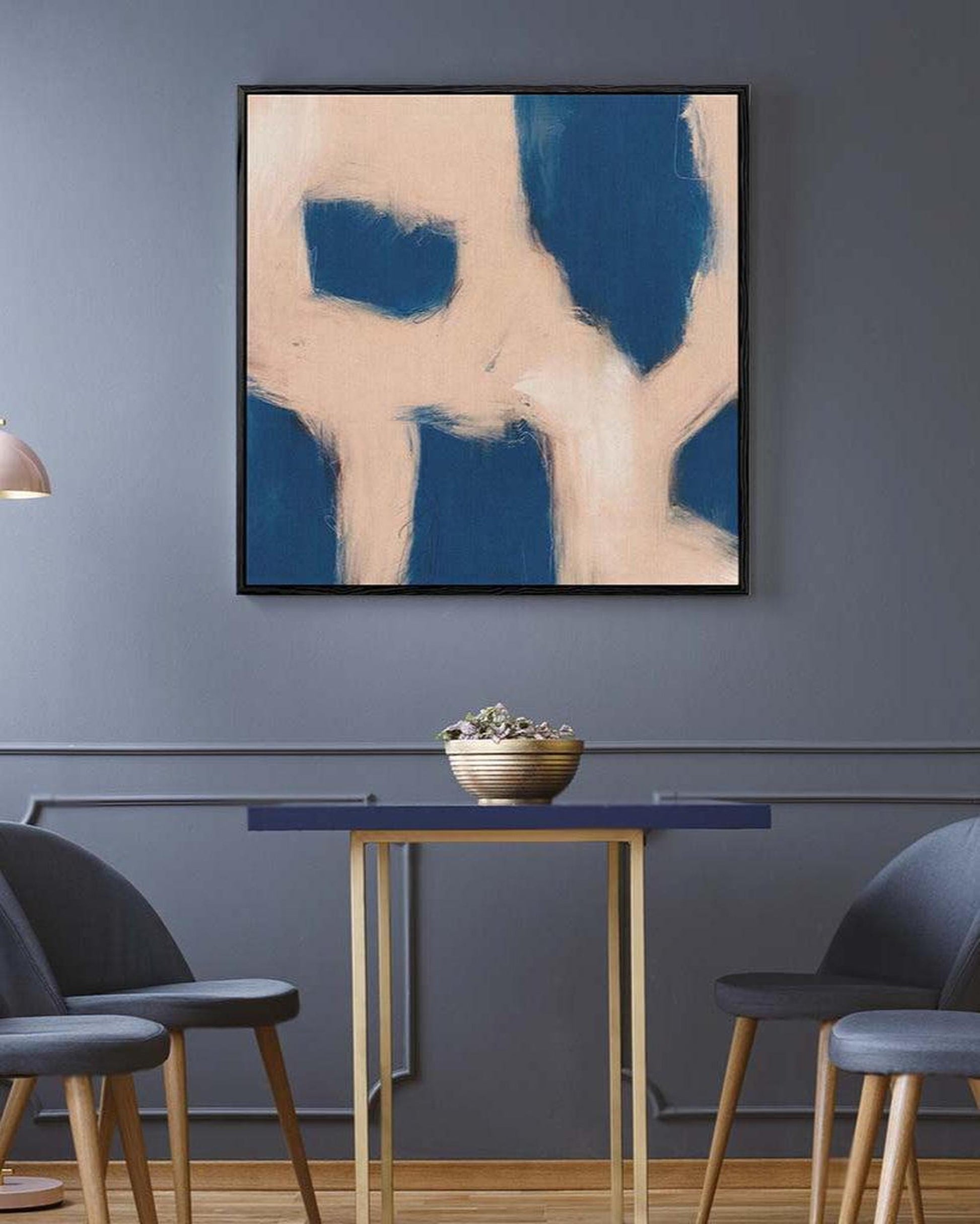 Abstract art piece on a wall above a dining table with chairs.