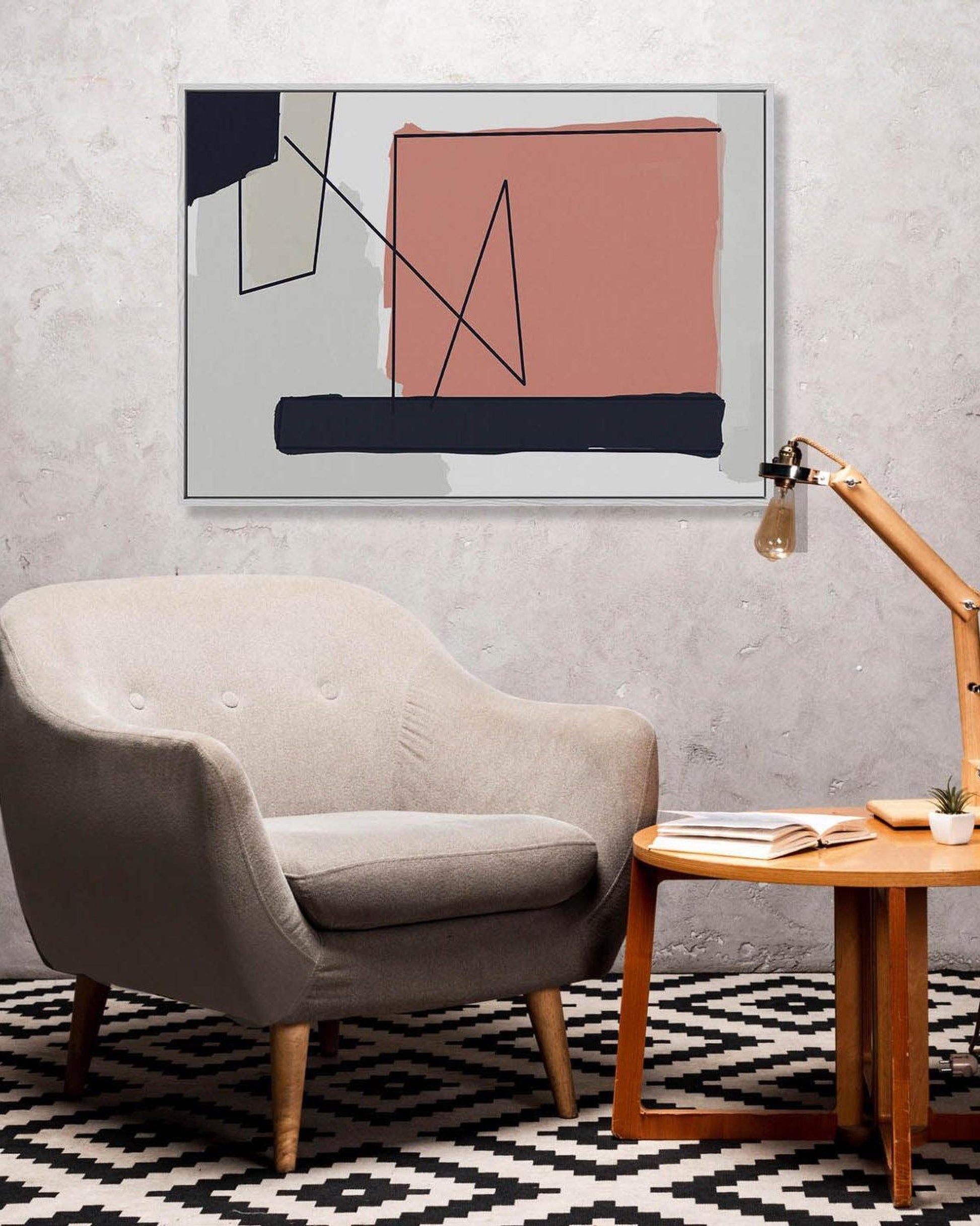 Modern living room with a gray armchair, wooden side table, and abstract art on the wall.