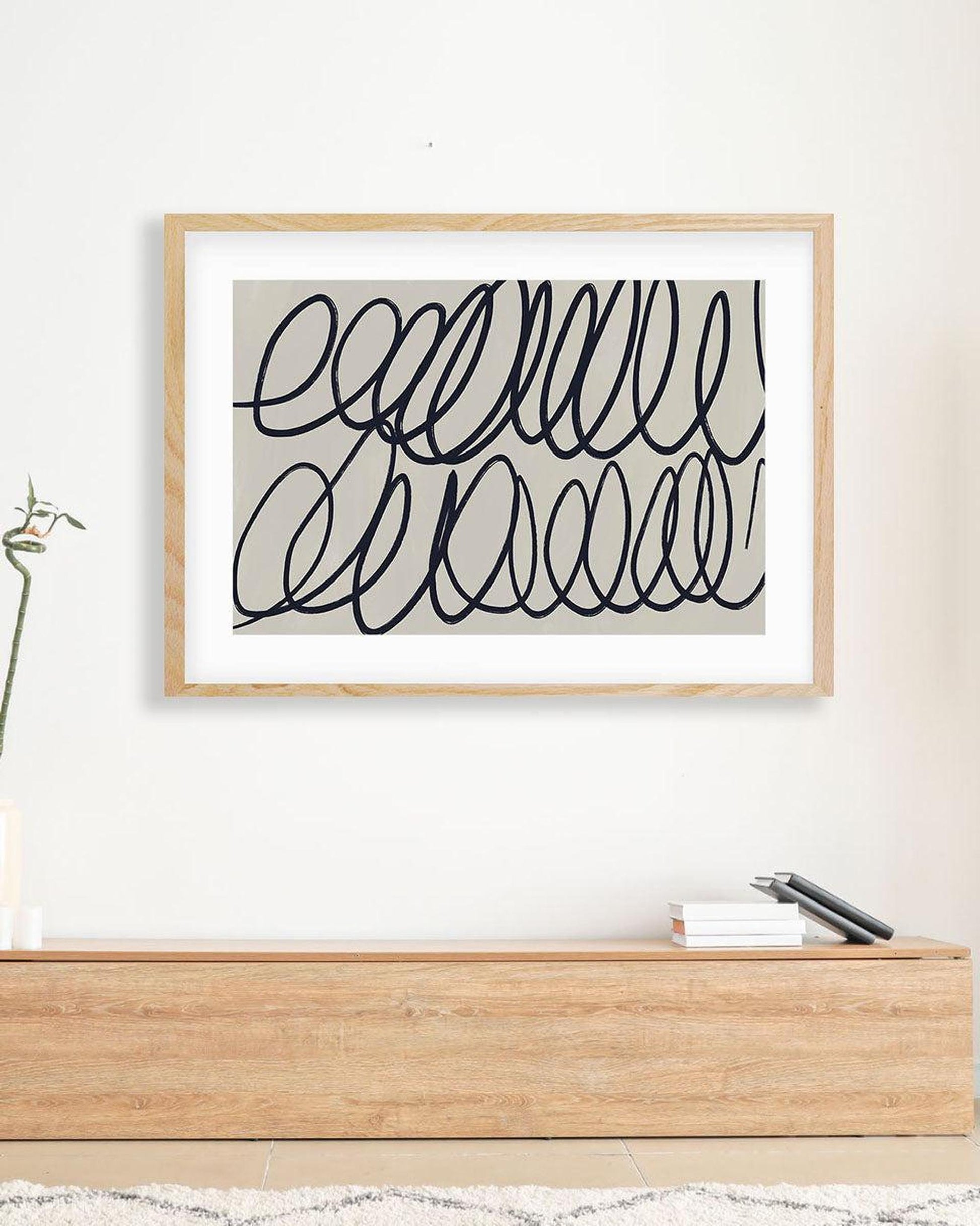 Framed abstract art print on a wall above a wooden console table.