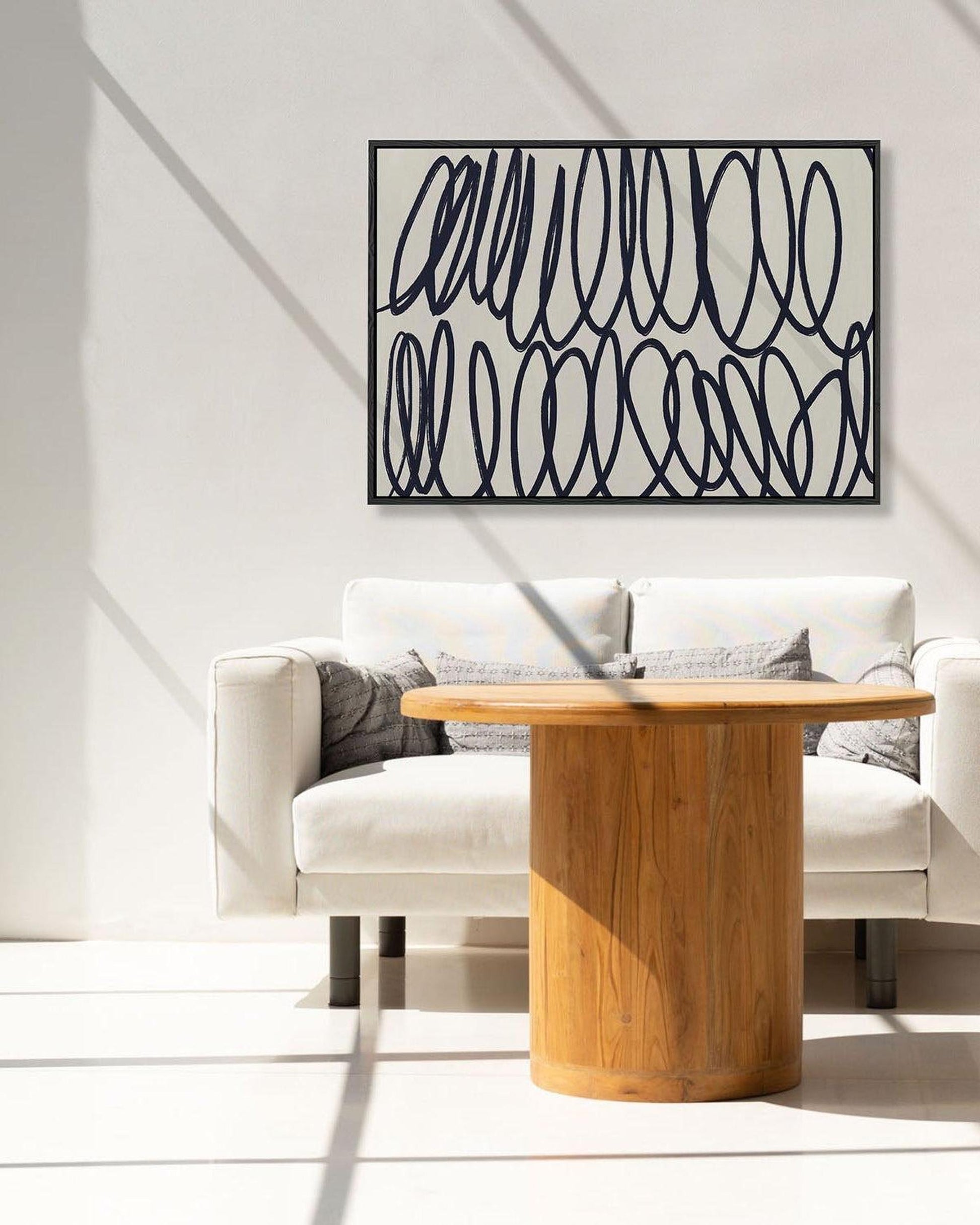 Modern living room with a wooden table and white sofa, featuring abstract wall art.