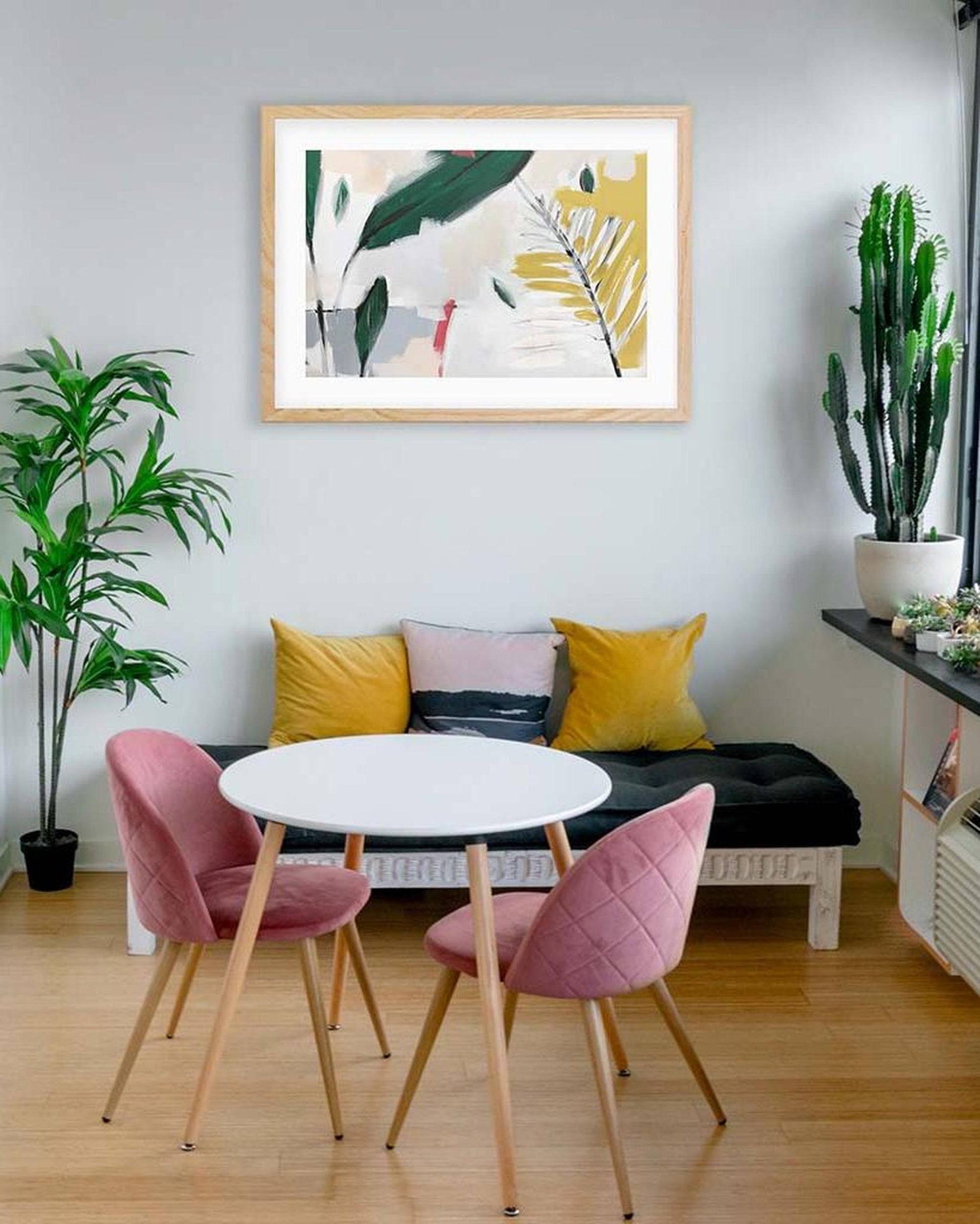 Modern living room with a round table, pink chairs, and abstract art on the wall.