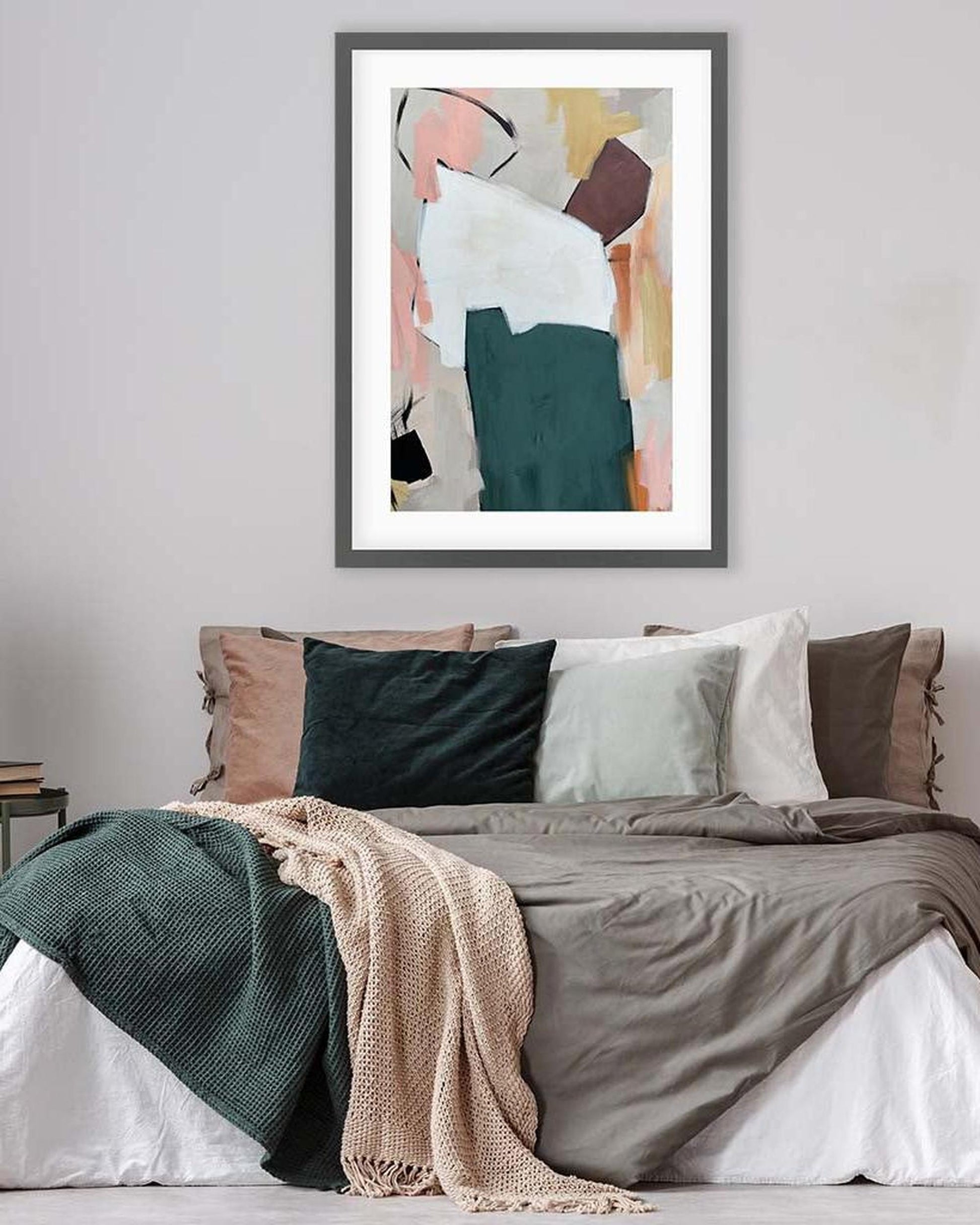 Abstract art print on a wall above a bed with colorful bedding.