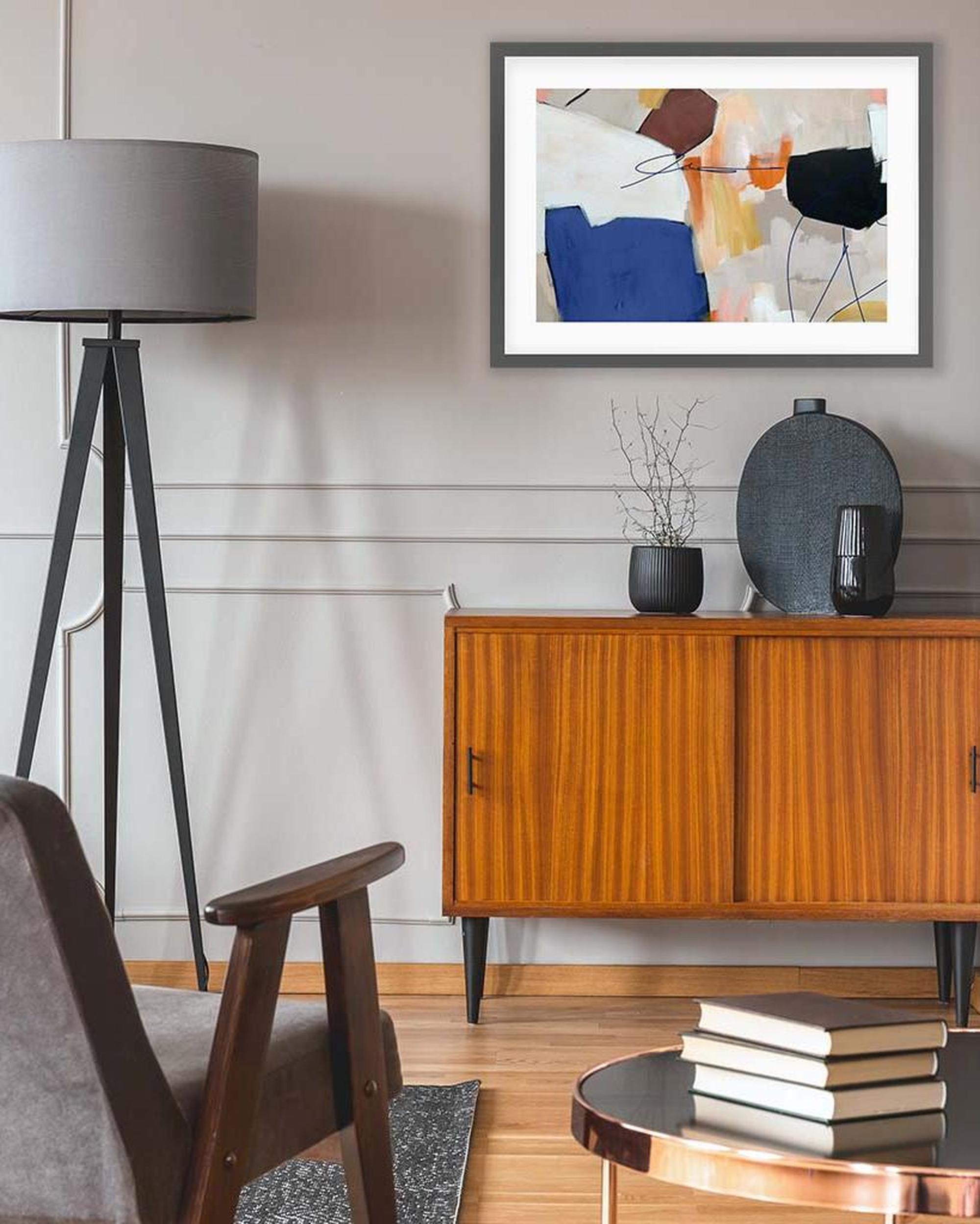 Living room with wooden cabinet, books, and abstract art on the wall.