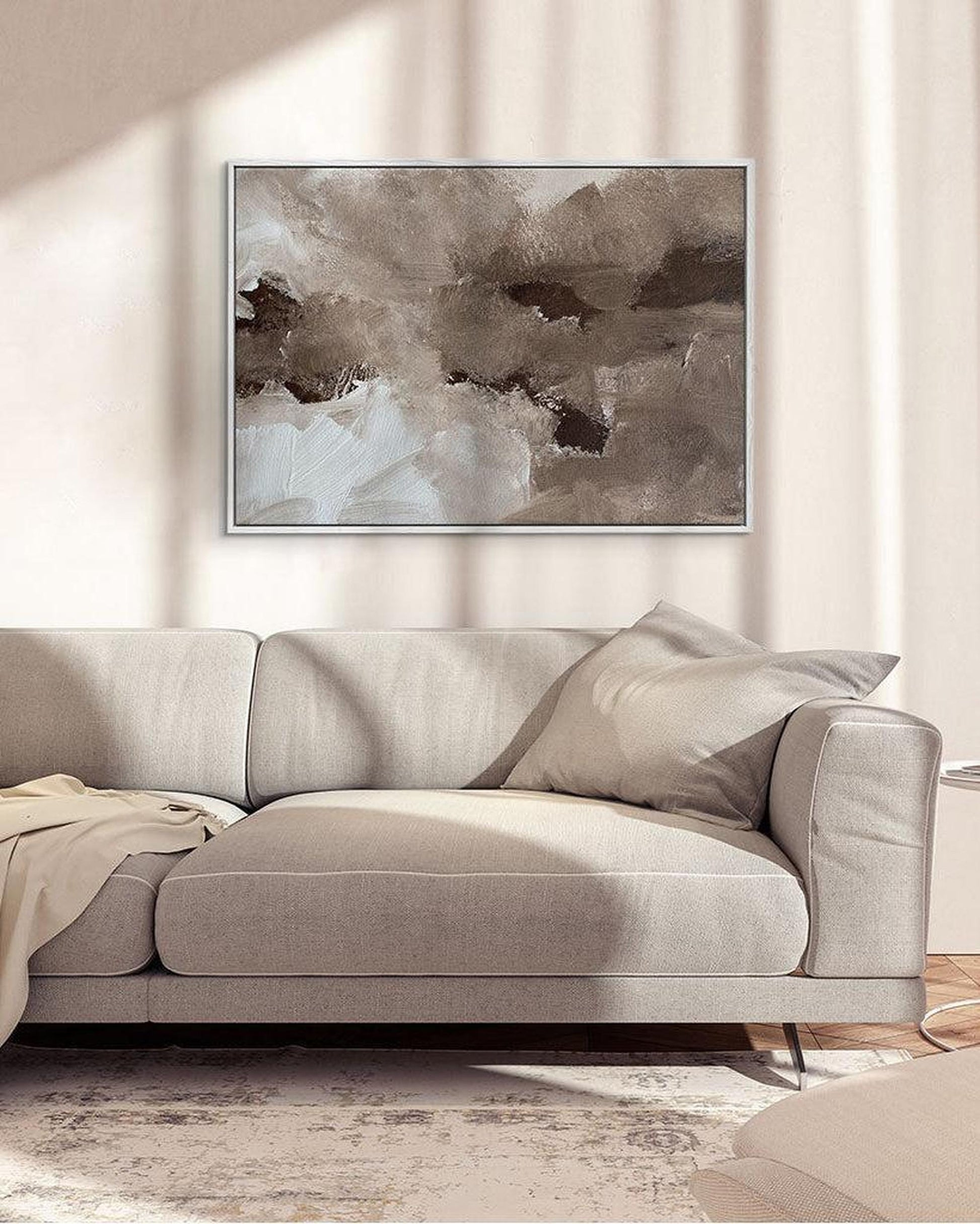 Gray sofa in a living room with a neutral abstract painting on the wall.