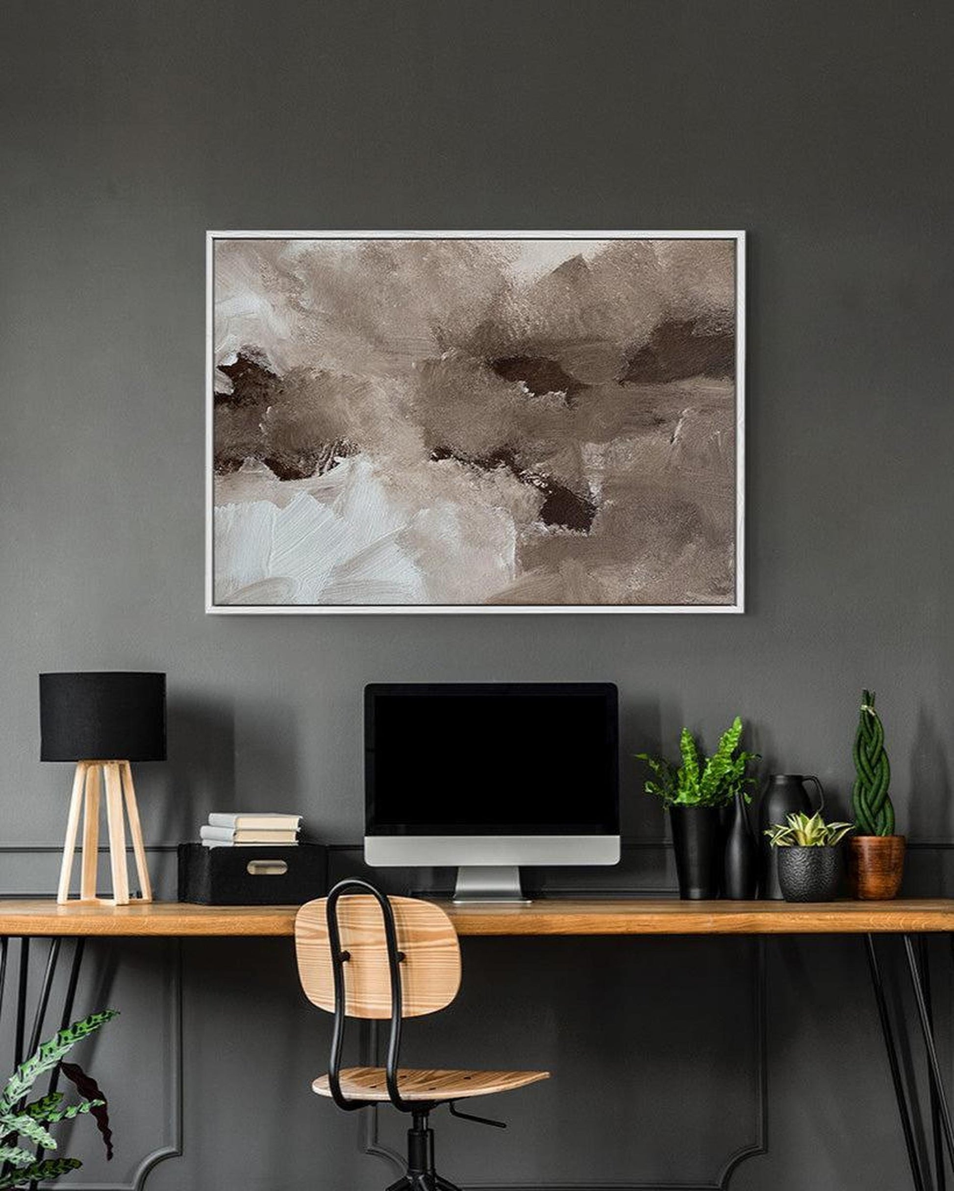 Modern home office with a desk, chair, computer monitor, and abstract art on a gray wall.