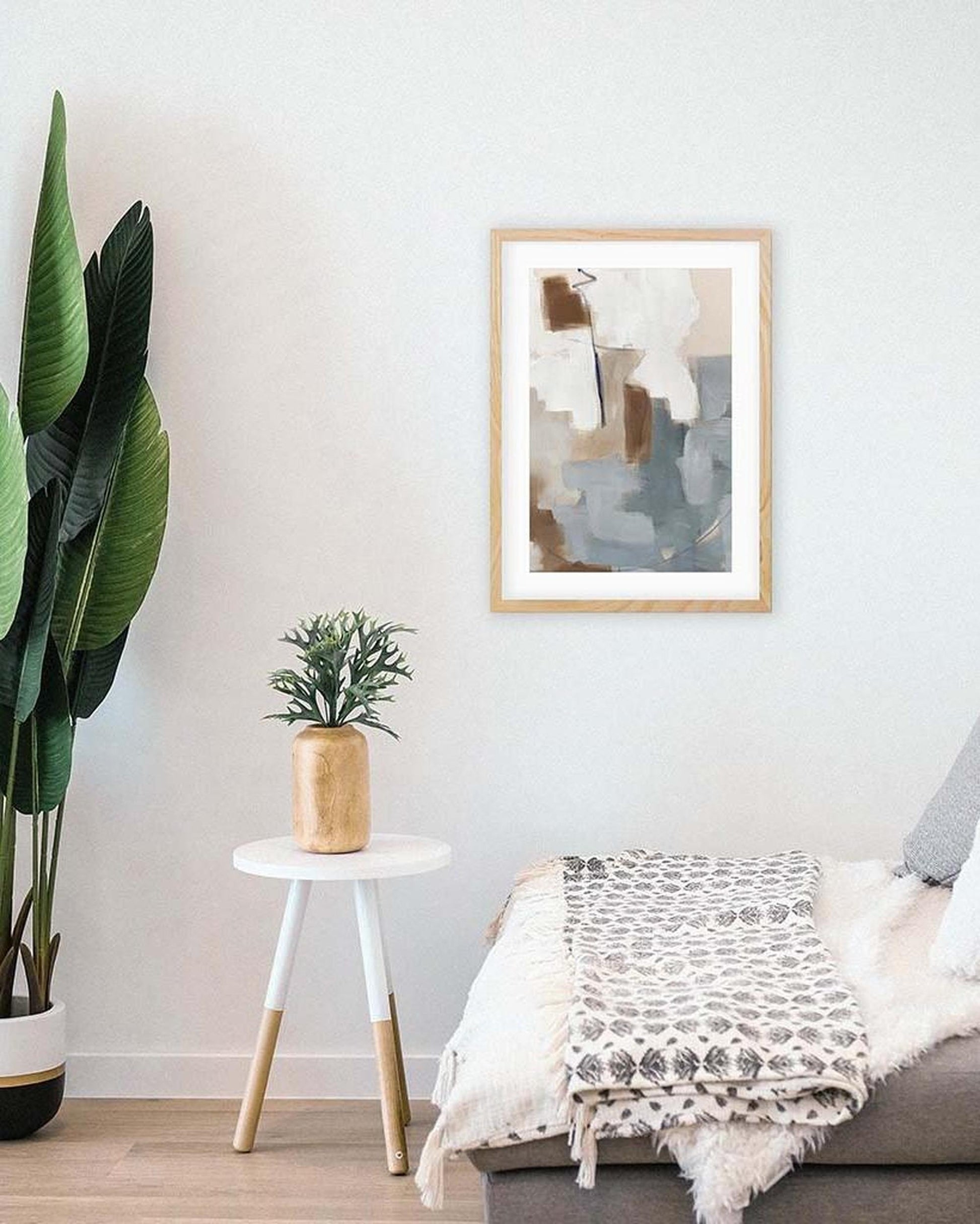 Living room with a couch, plant, small table, and abstract art on the wall.