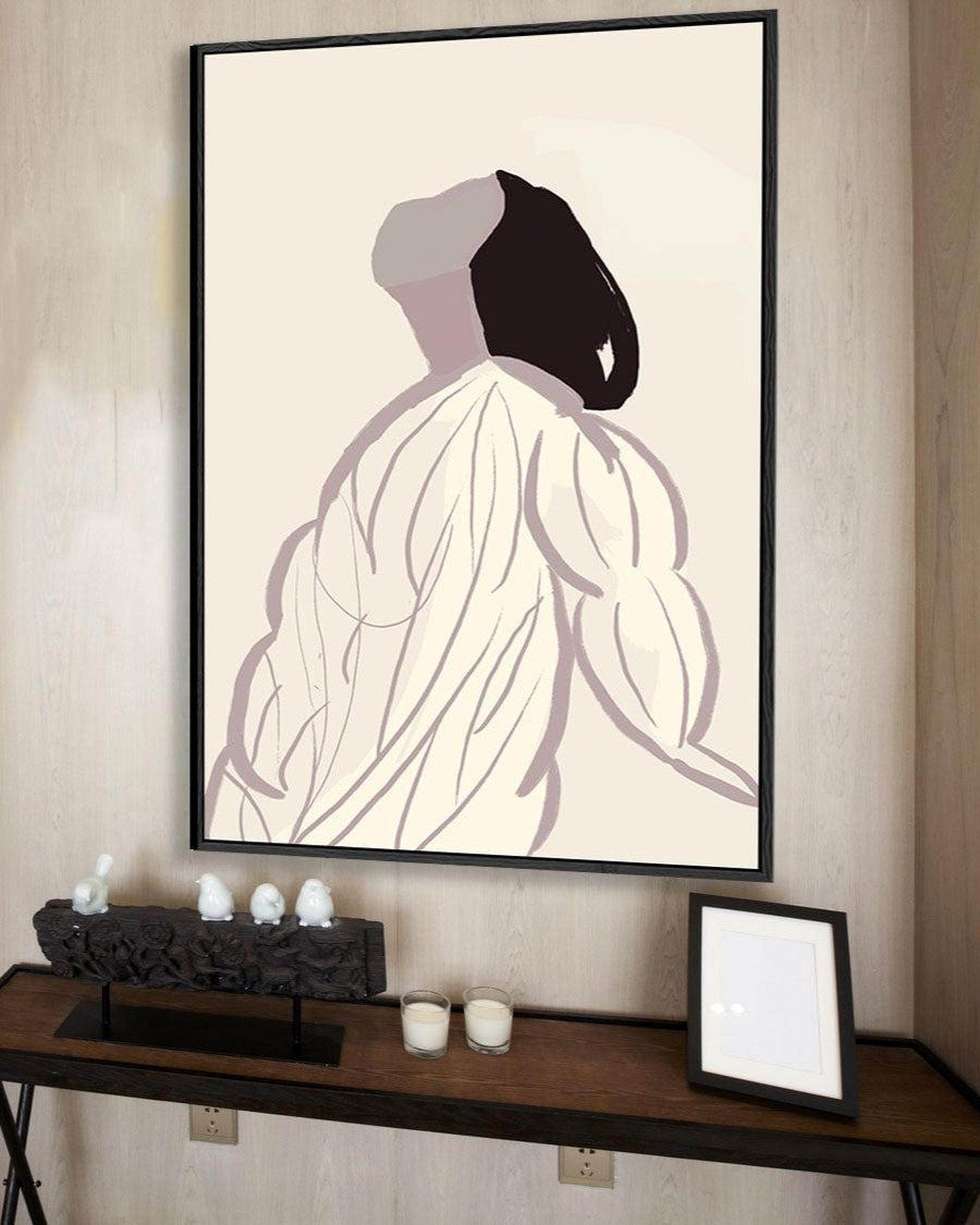 Framed abstract art of a draped figure on a wall above a console table.