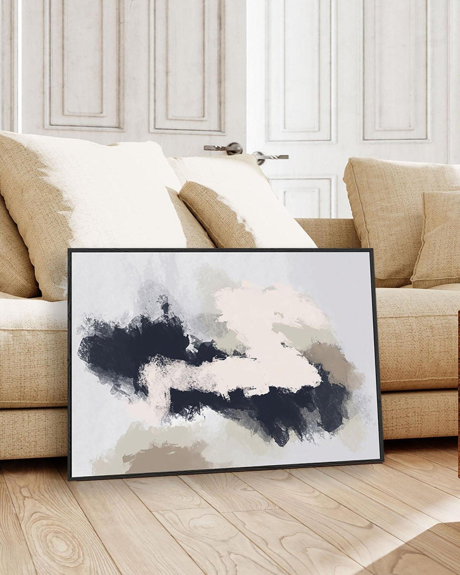 Abstract art print on a wooden floor with a beige sofa in the background