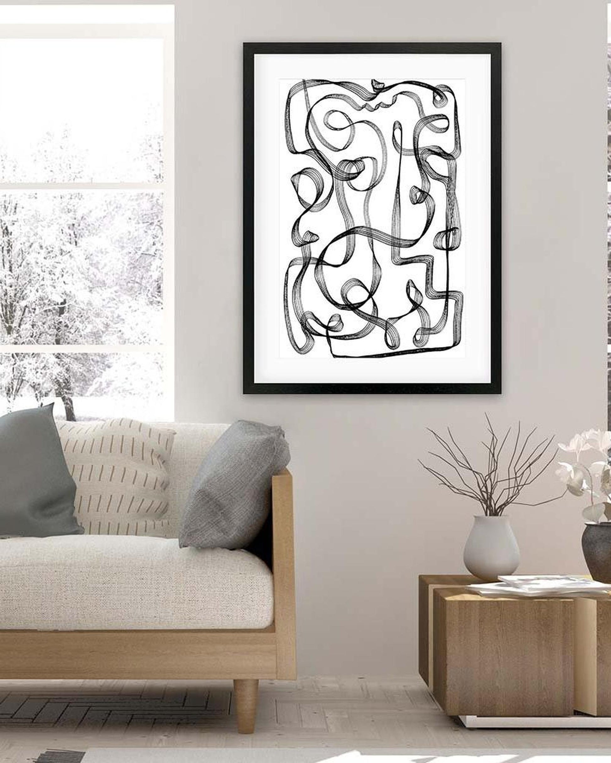 Abstract black and white artwork on a wall above a sofa in a living room.