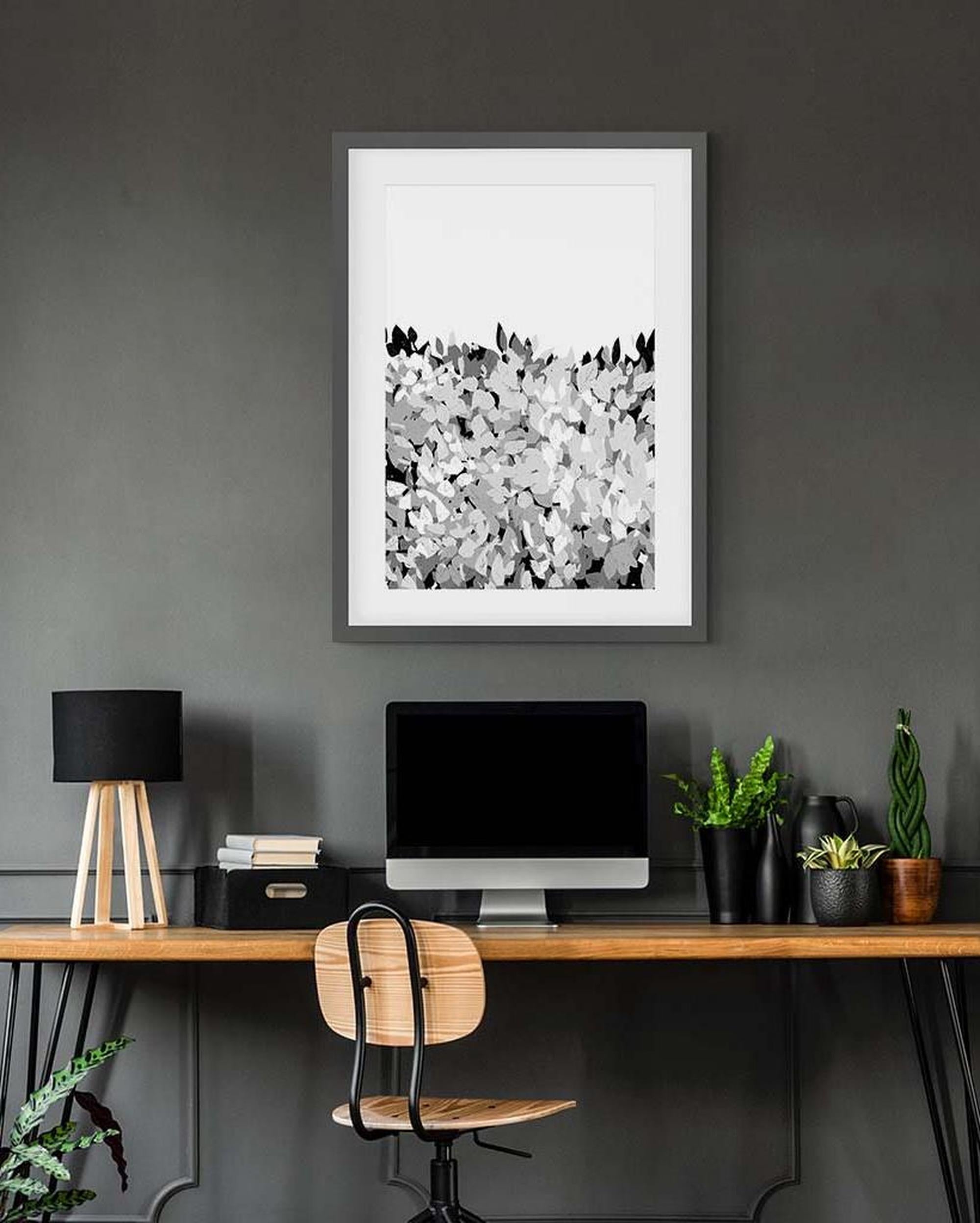 Modern office setup with a framed abstract artwork on a gray wall.