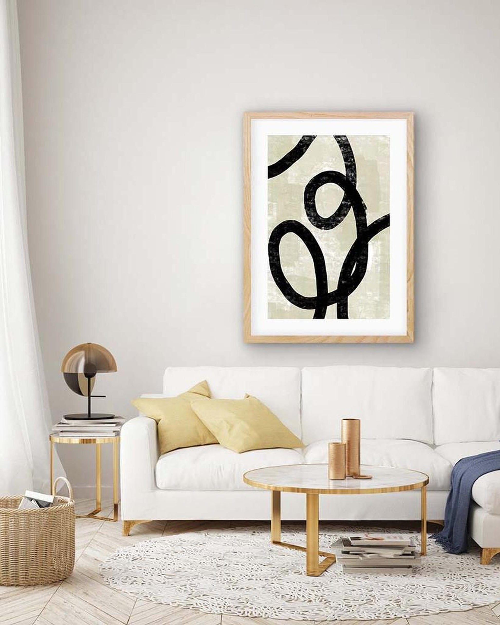 Modern living room with a white sofa, gold coffee table, and abstract art on the wall.