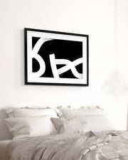 Framed black and white abstract art above a bed