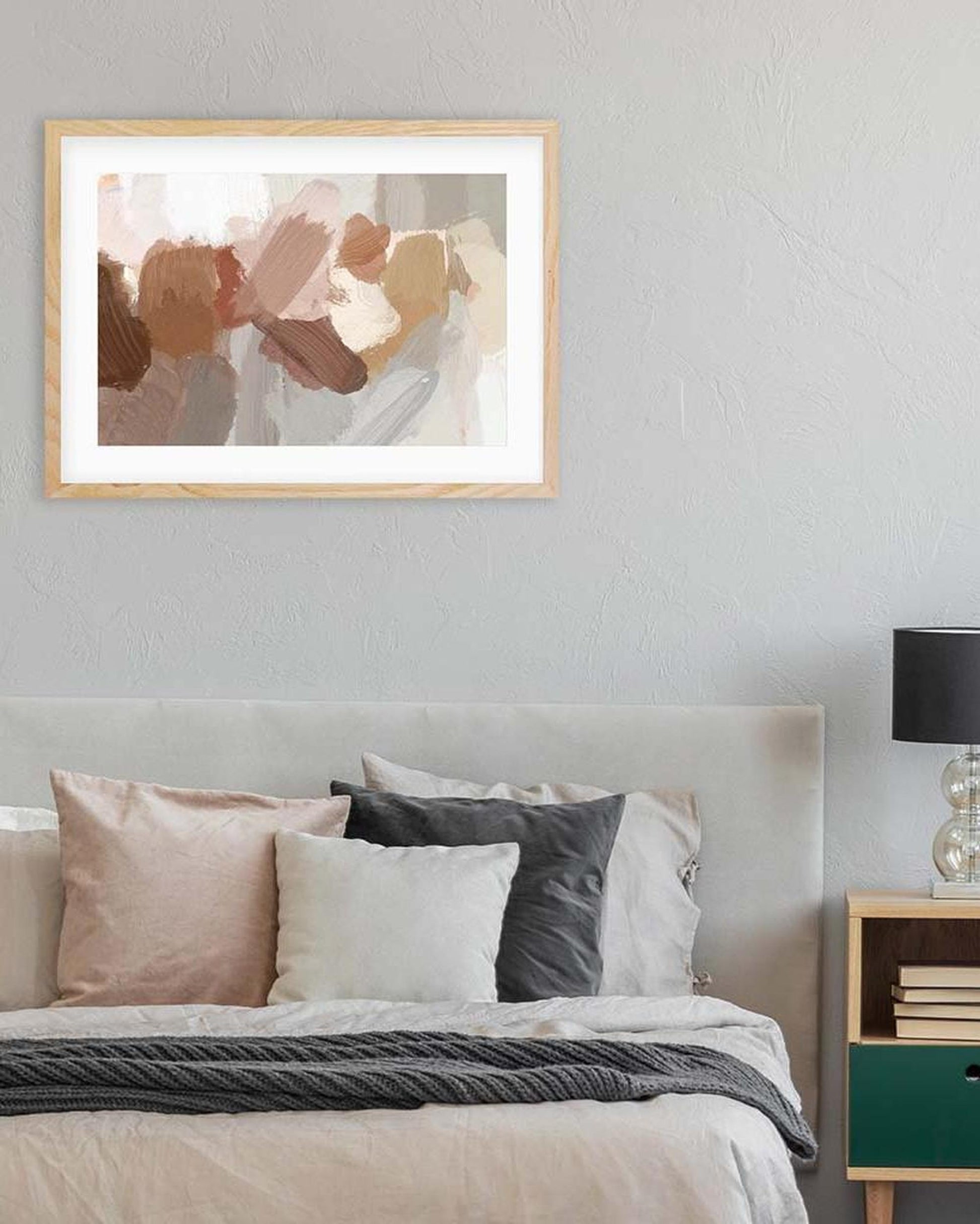 Framed abstract art above a bed in a bedroom setting