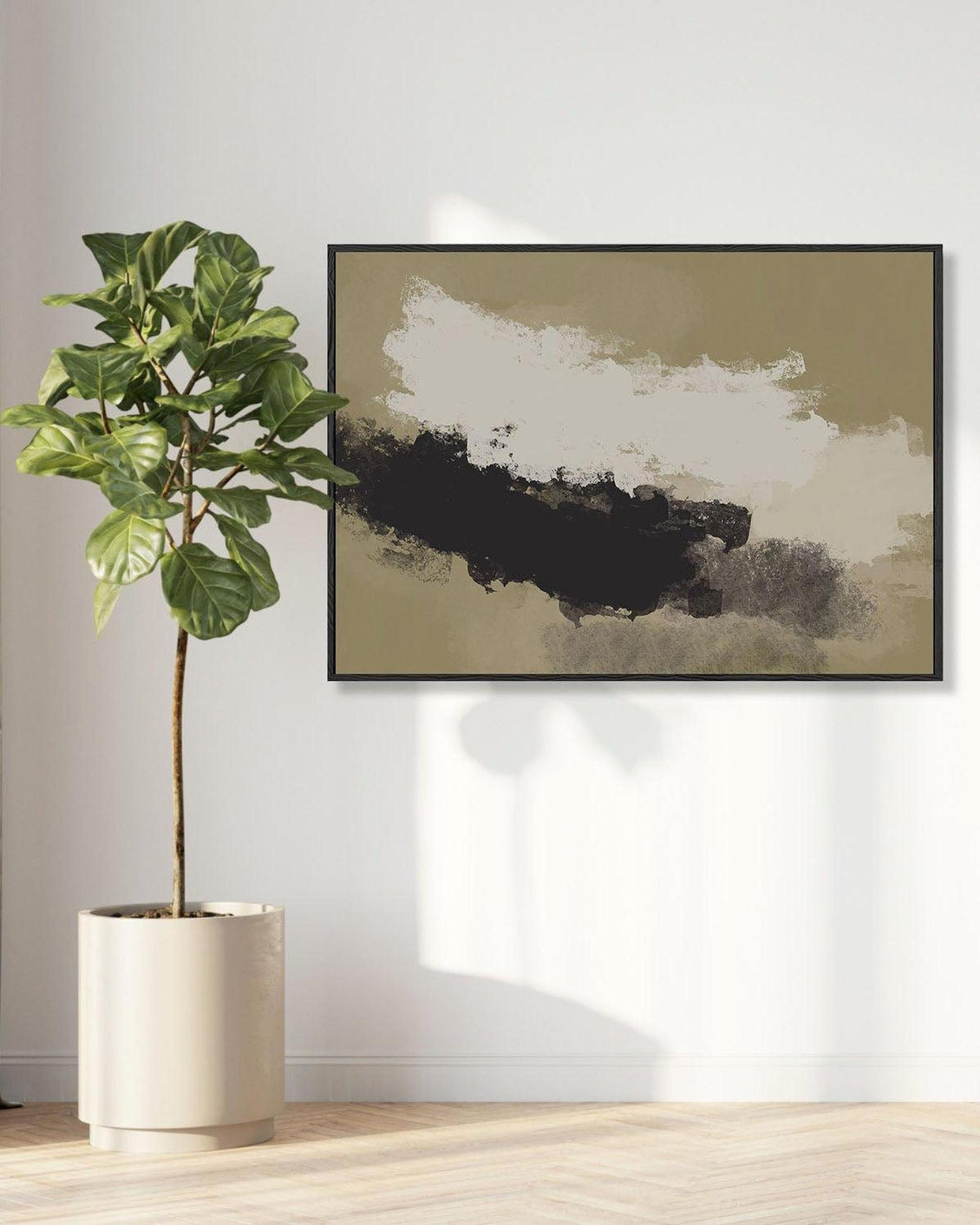 Fiddle leaf fig plant in a pot next to a framed abstract art piece on a wall.
